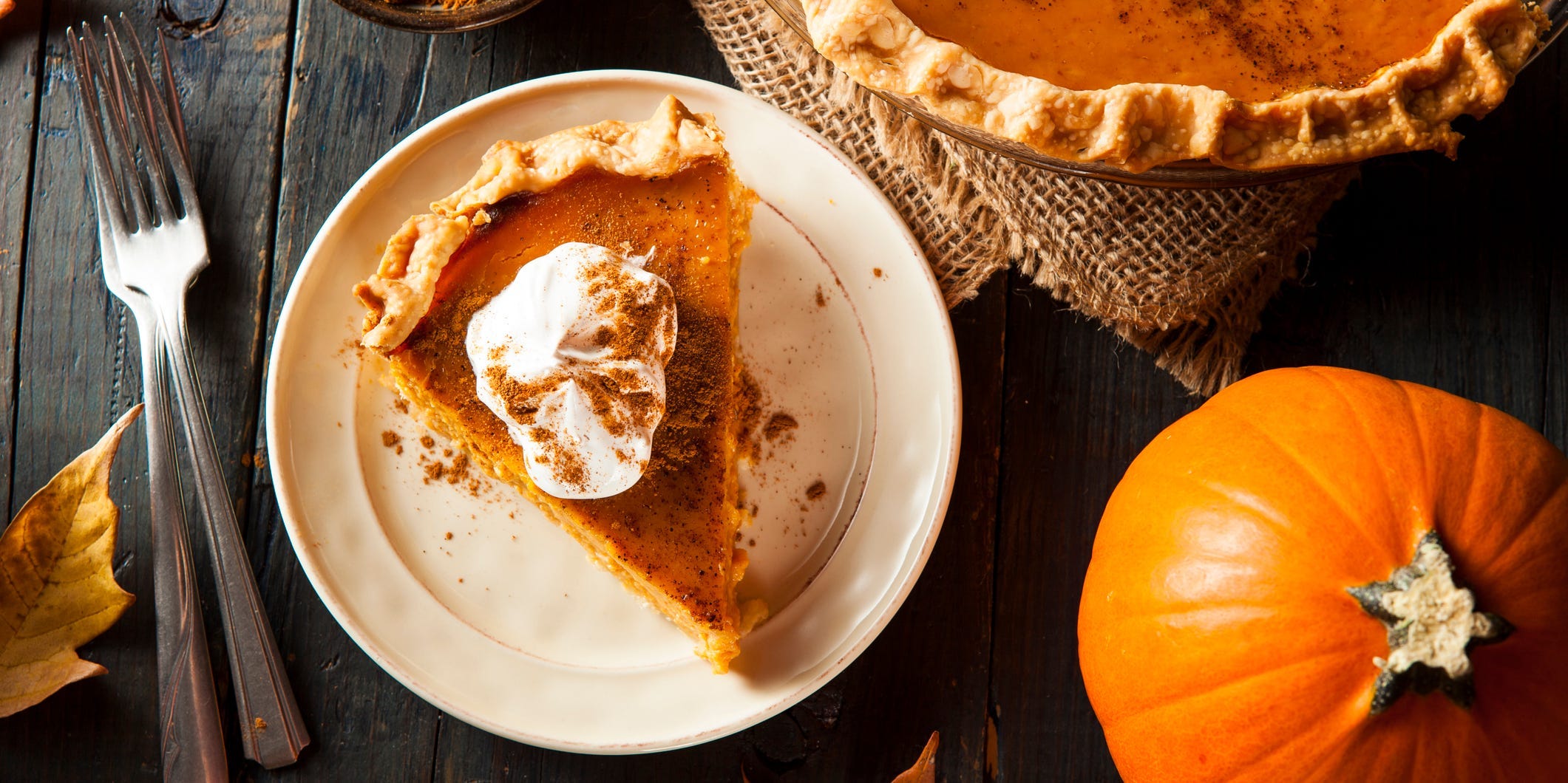 A slice of pumpkin pie on a plate topped with whipped cream