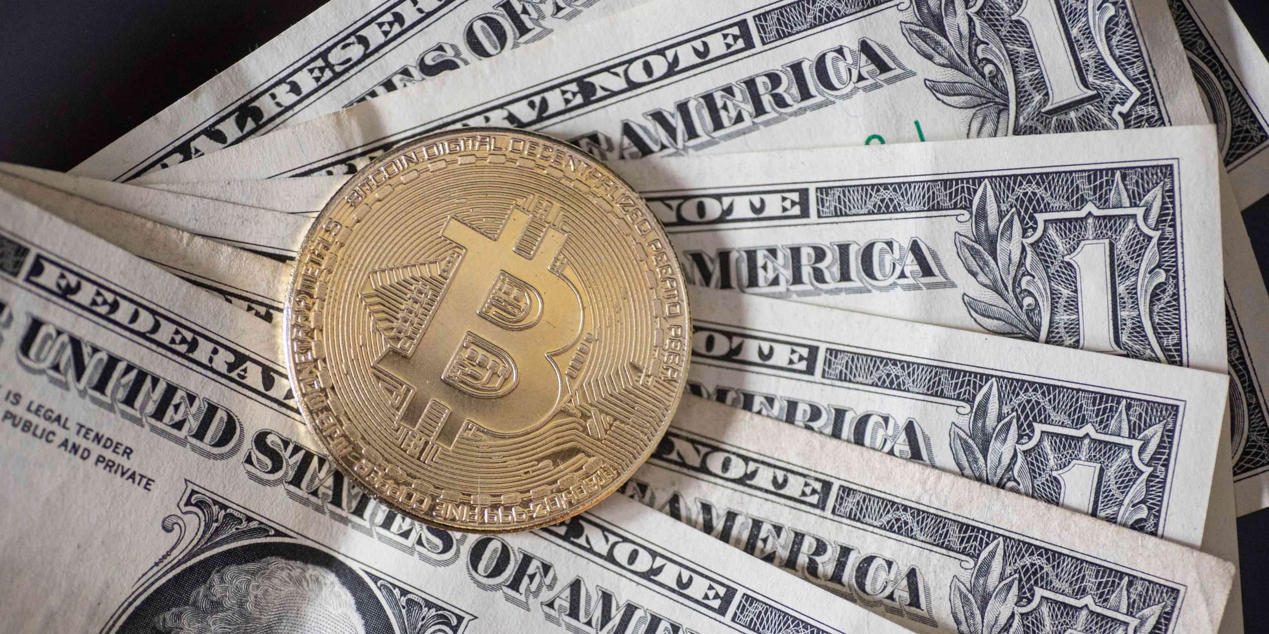 Bitcoin golden physical coin illustration on United States Dollar banknotes.