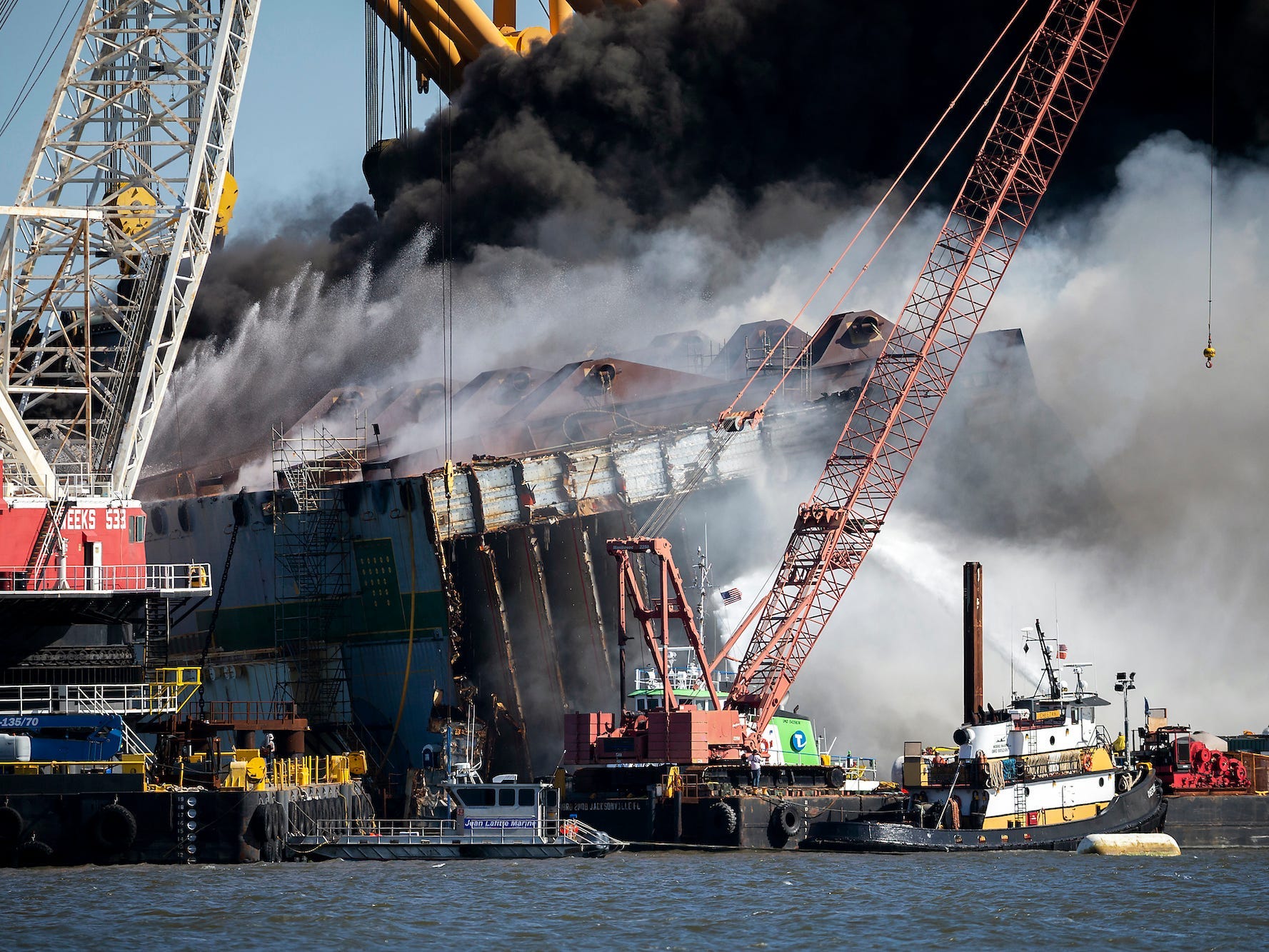 Firefighters spray water into the cut away mid-section of the cargo vessel Golden Ray, Friday, May 14, 2021, Brunswick, Ga.