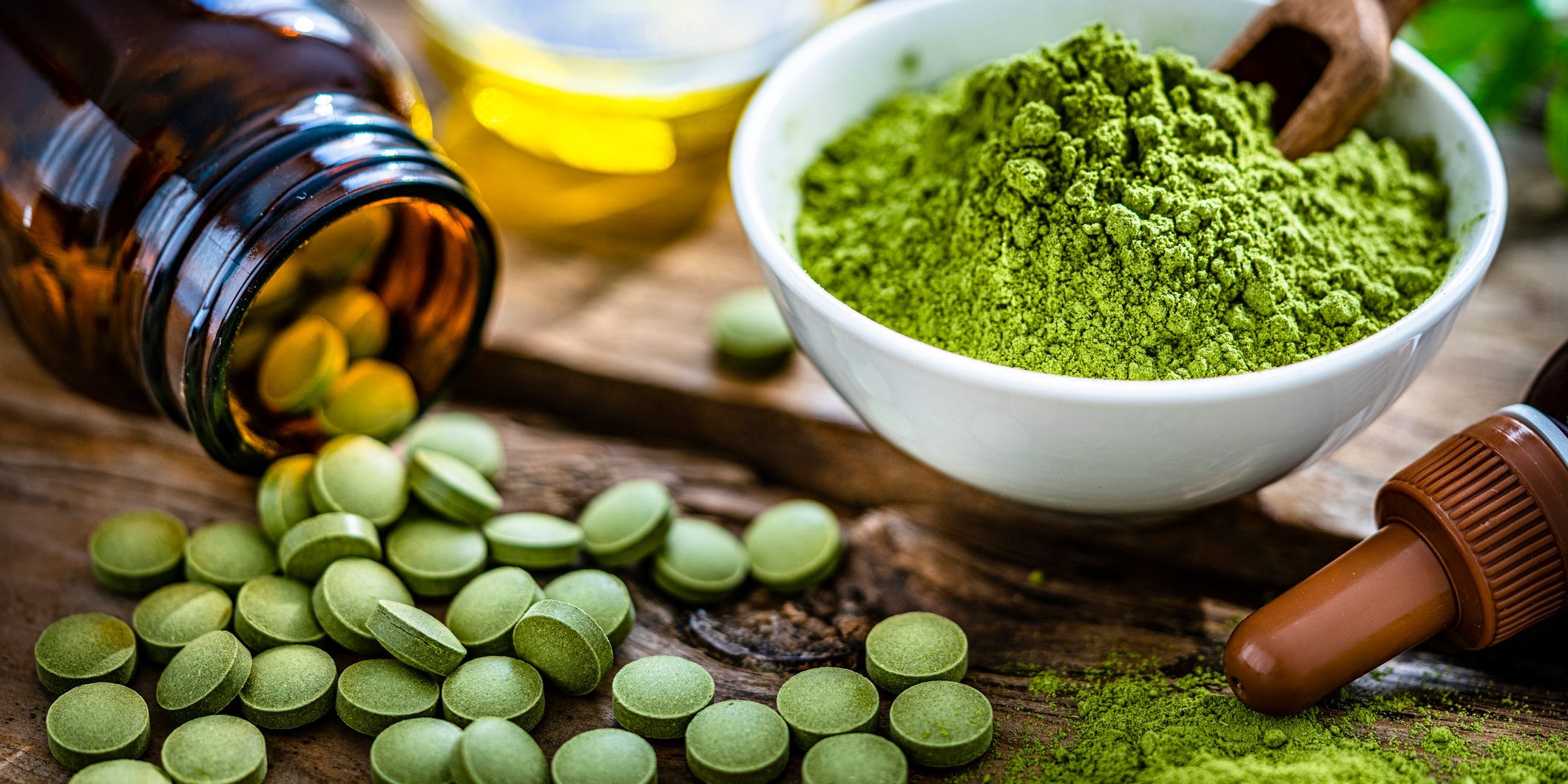Image of moringa capsules, powder, and oil spread across a wood table.