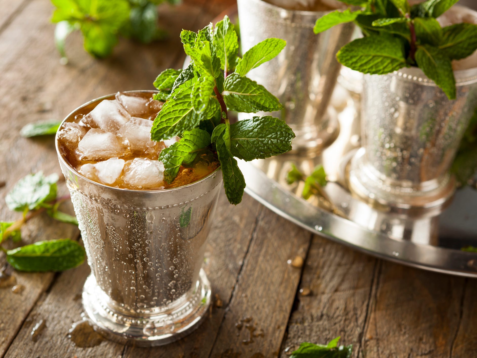 A mint julep in a metal cup garnished with mint leaves