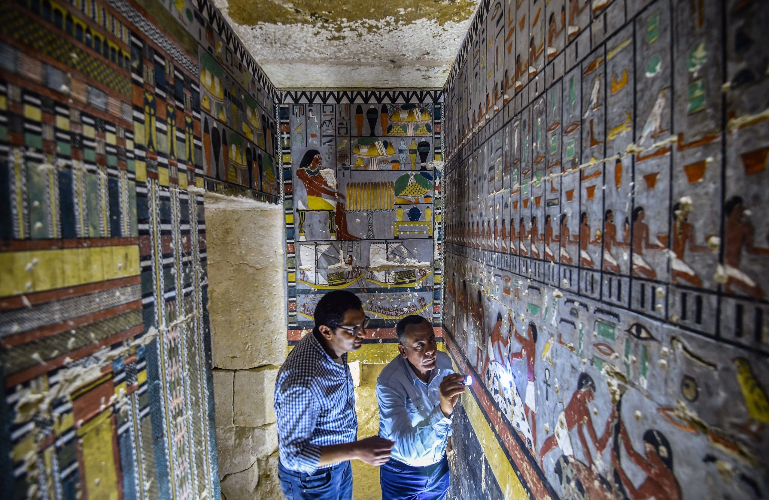 Mohamed Mujahid (L), head of the Egyptian mission which discovered the tomb of the ancient Egyptian nobleman Khuwy inspects the tomb's walls inside at the Saqqara necropolis on April 13, 2019. (