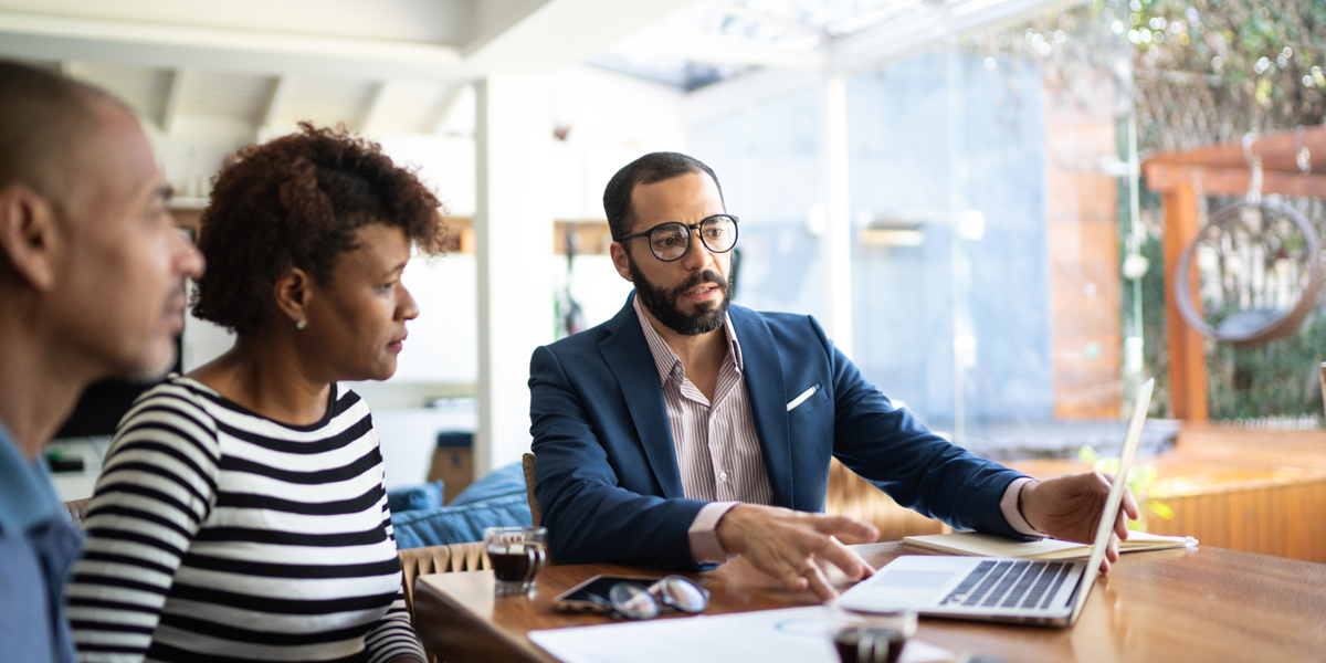 A couple talking to a financial adviser in their home.