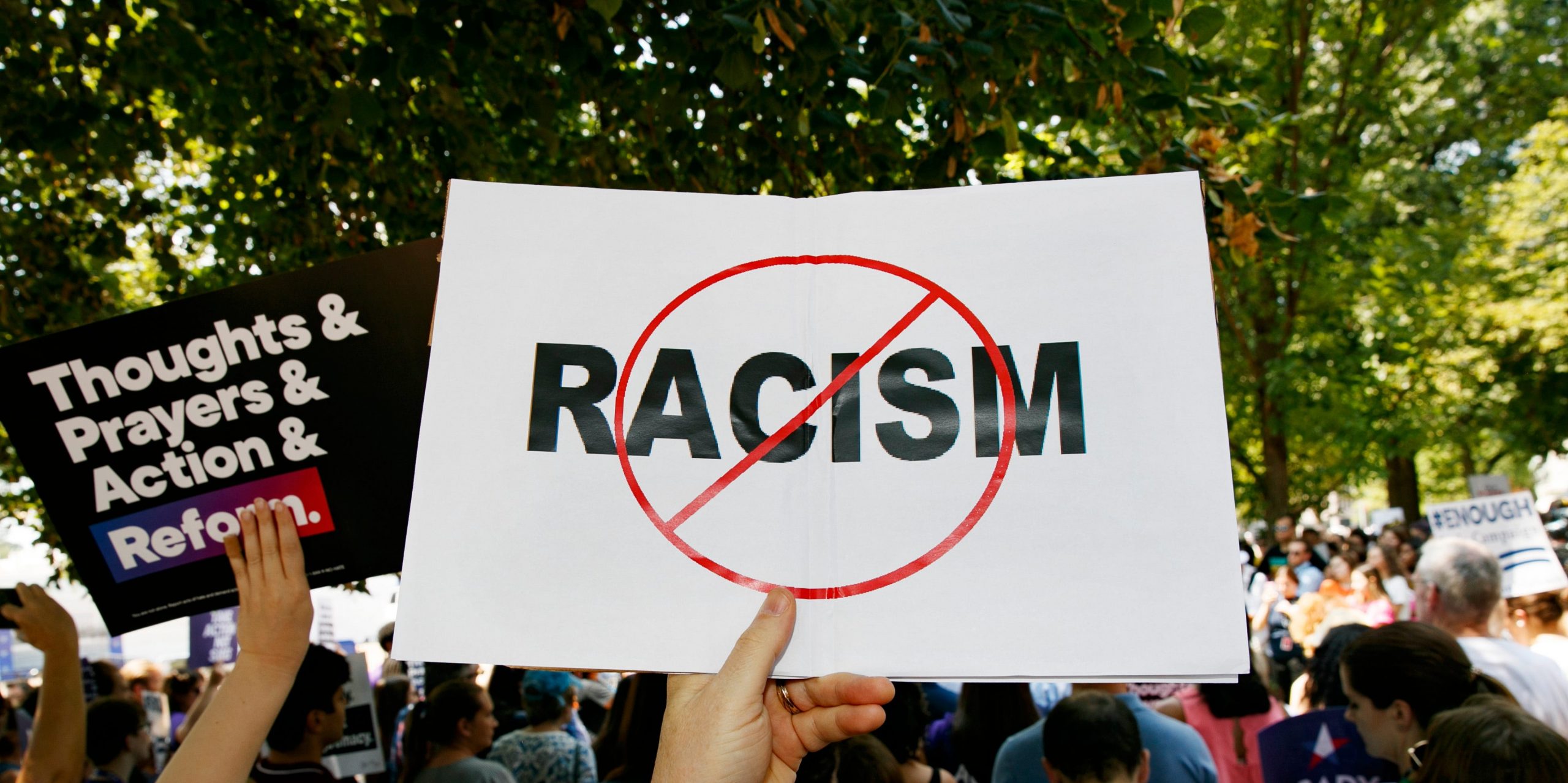 A man holds up an anti-racism sign.