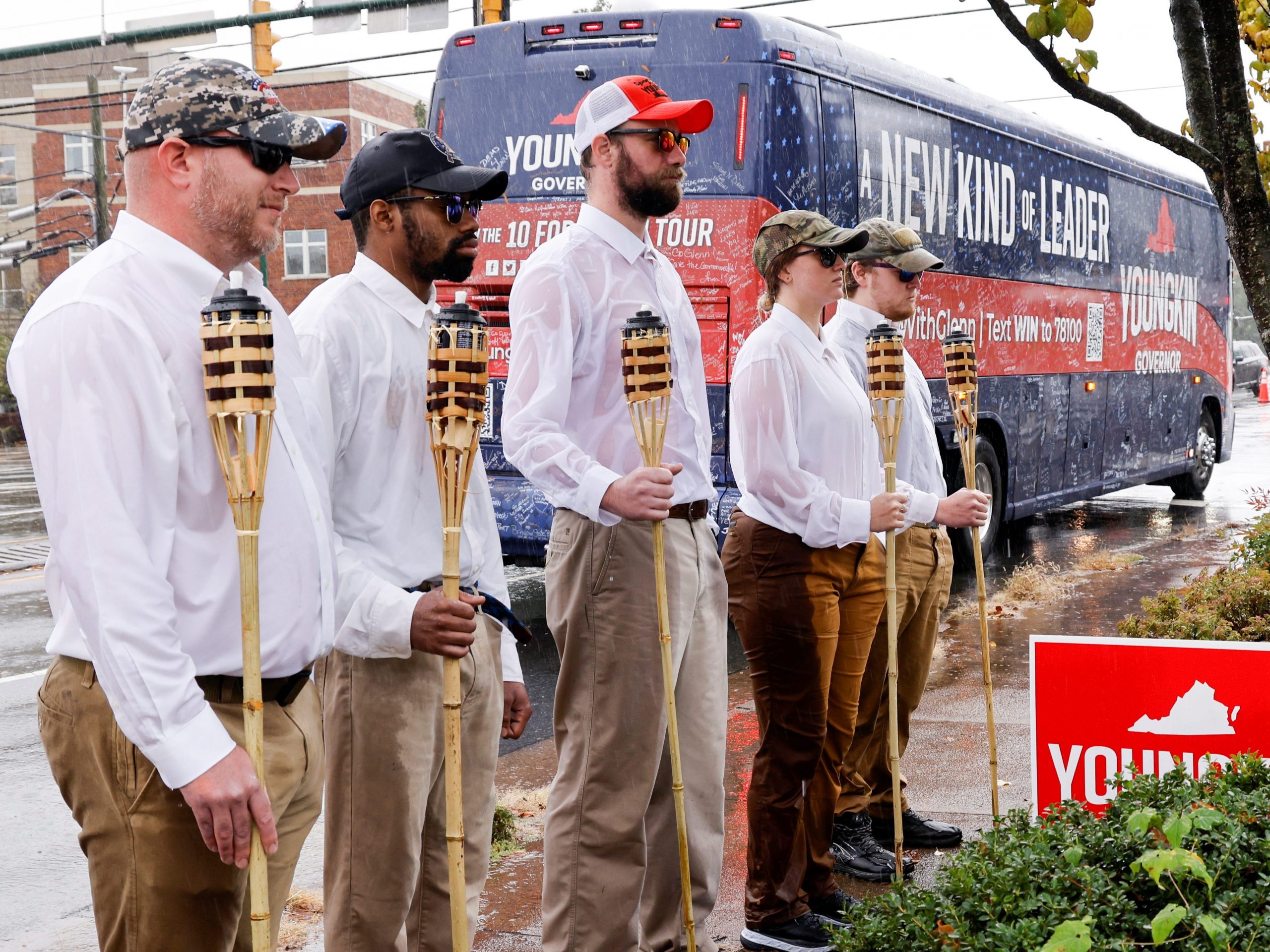 A small group of demonstrators dressed as "Unite the Right" rally-goers with tiki torches stand on a sidewalk as Republican candidate for governor of Virginia Glenn Youngkin arrives on his bus for a campaign event at a Mexican restaurant in Charlottesville, Virginia, U.S. October 29, 2021.