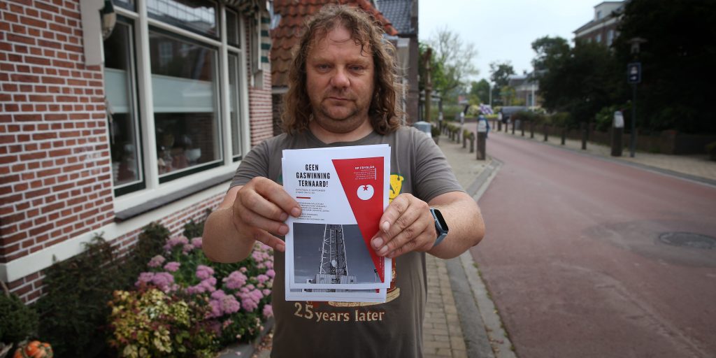 Een inwoner van het Friese dorp Ternaard houdt een pamflet vast waarop het protest tegen gaswinning wordt aangekondigd.
