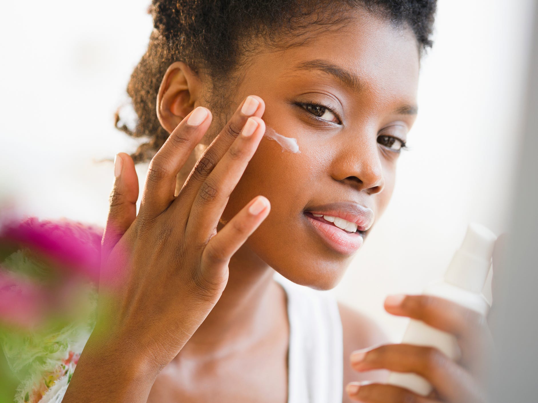 woman applying sunscreen or moisturizer to face