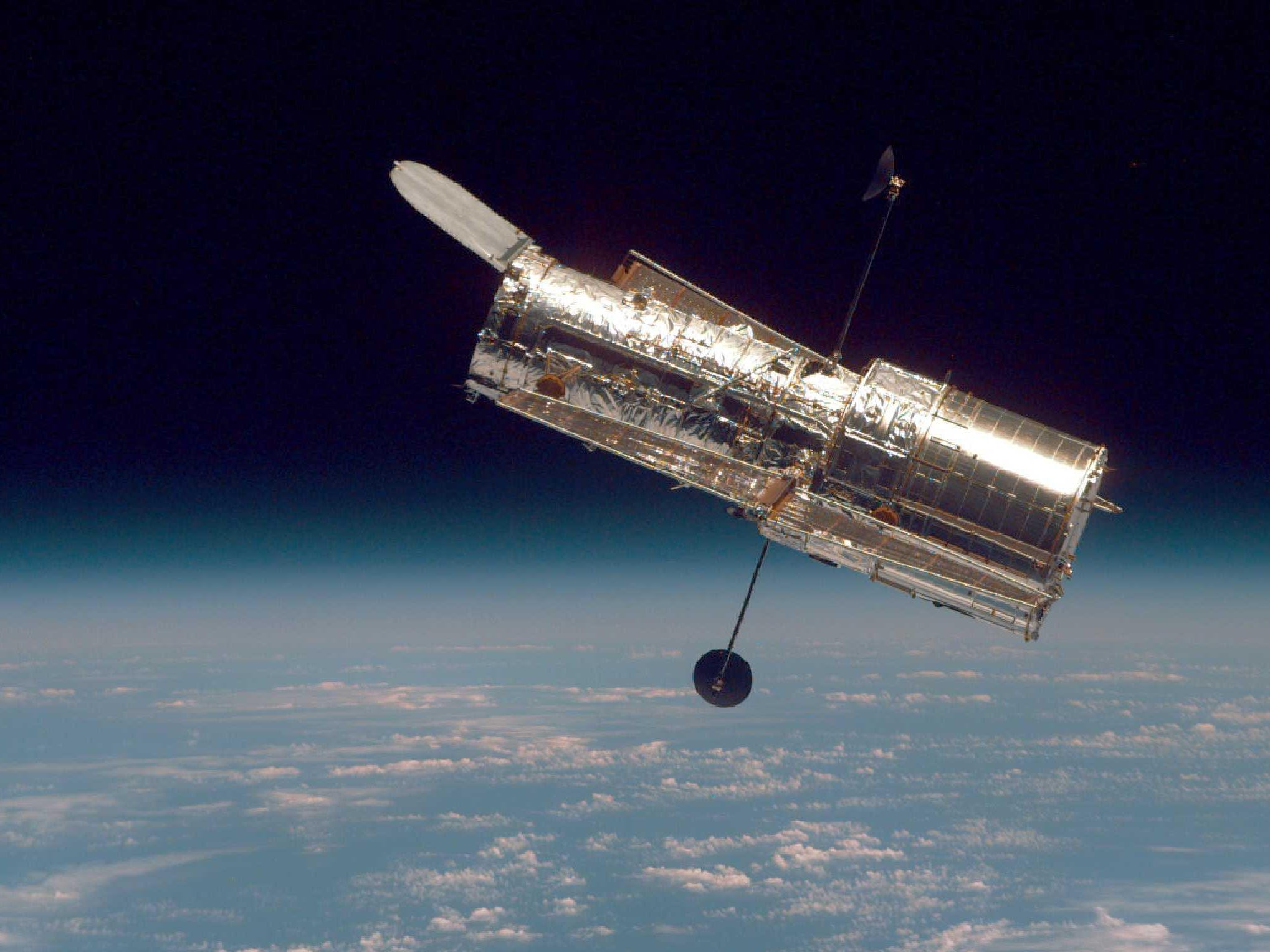 hubble telescope in space above earth clouds