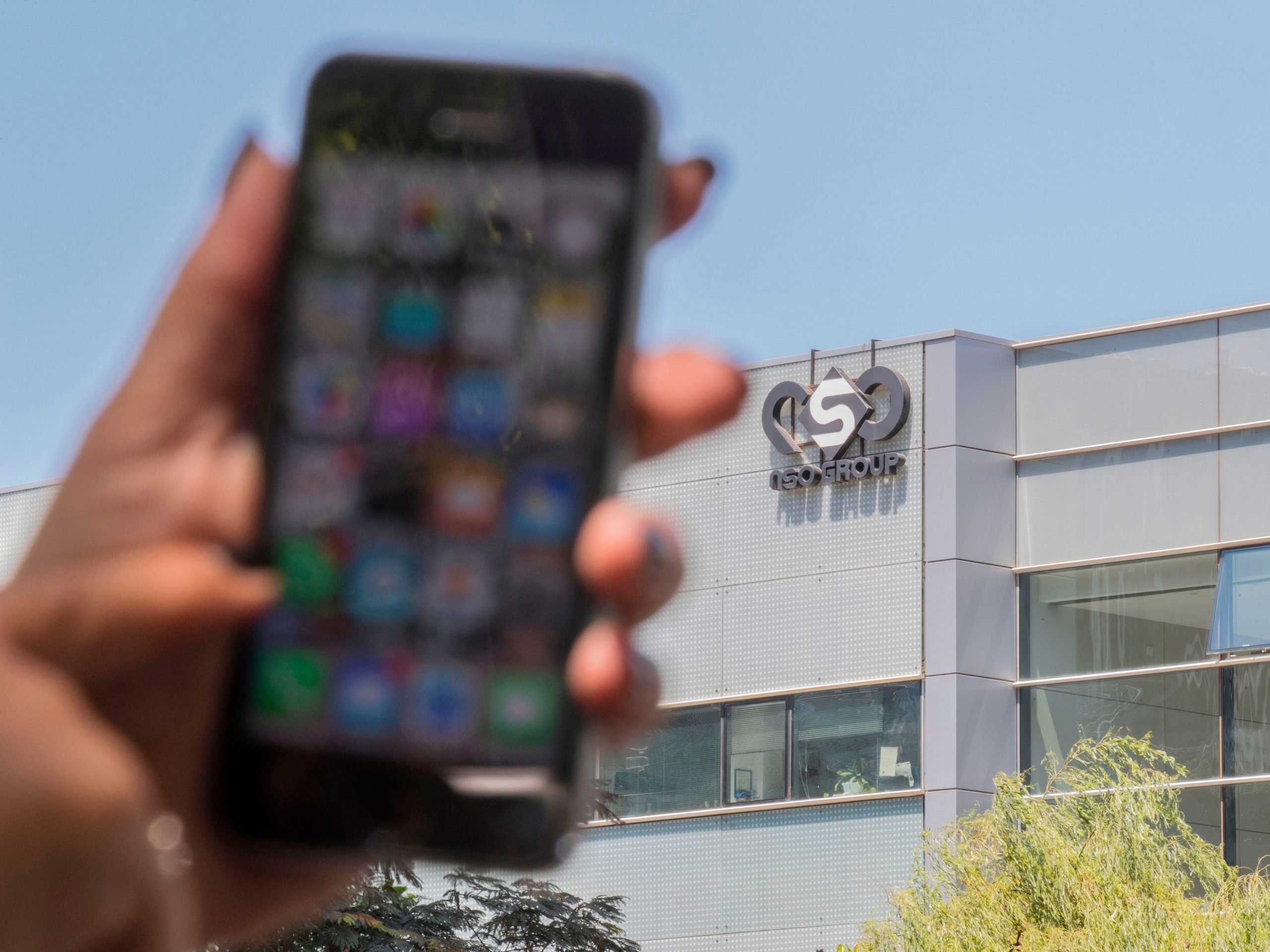 Woman holds phone outside NSO Group in Herzliya