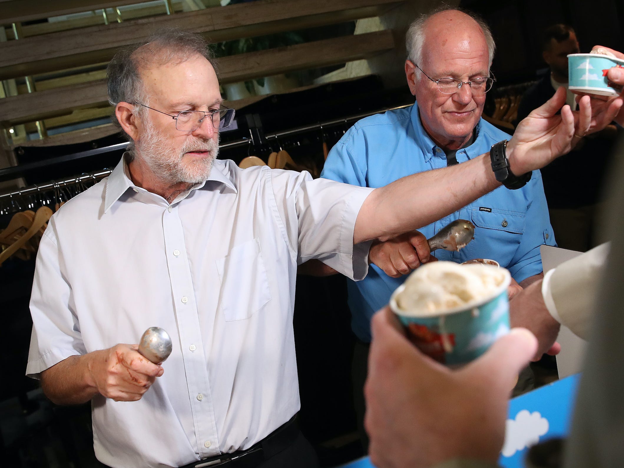 Ben & Jerry's co-founders Ben Cohen (R) and Jerry Greenfield (L) serve ice cream following a press conference announcing a new flavor, Justice Remix'd.
