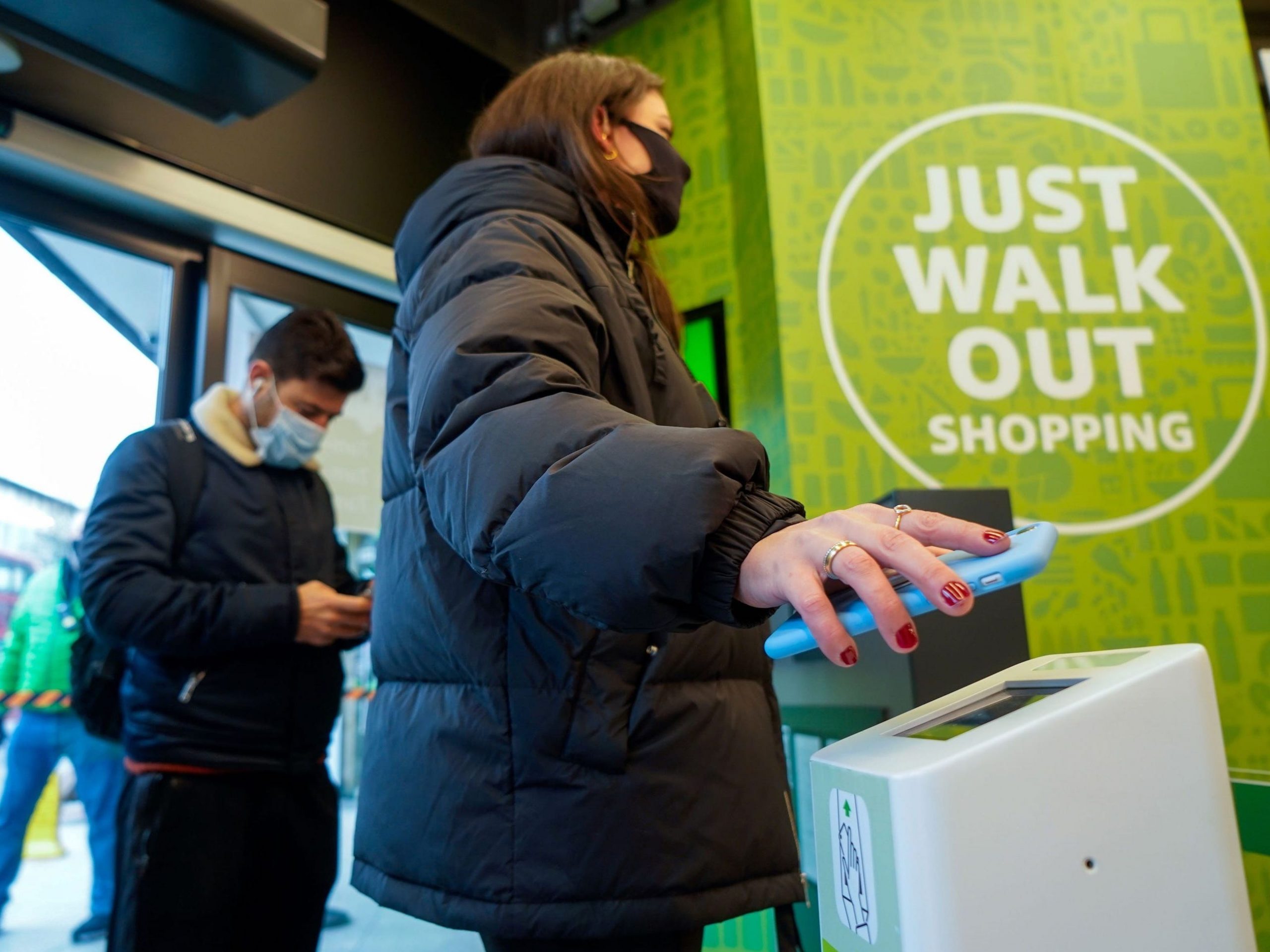 A customer scans her phone as she enters Amazon's new Amazon Fresh store in Ealing, west London, on March 4, 2021.