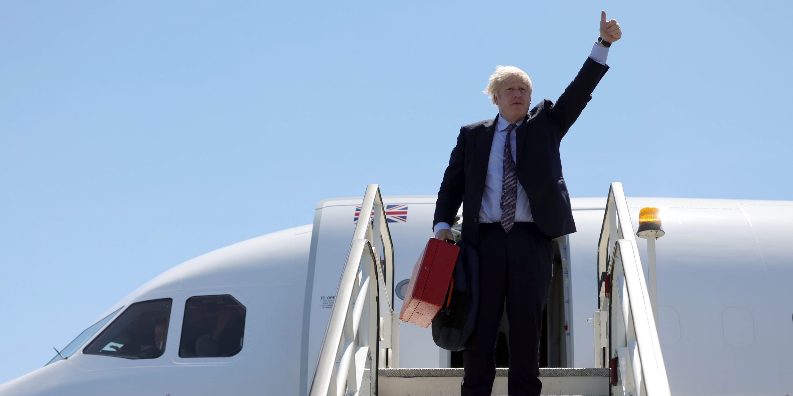 Boris Johnson gives a thumbs-up from the steps of an aircraft