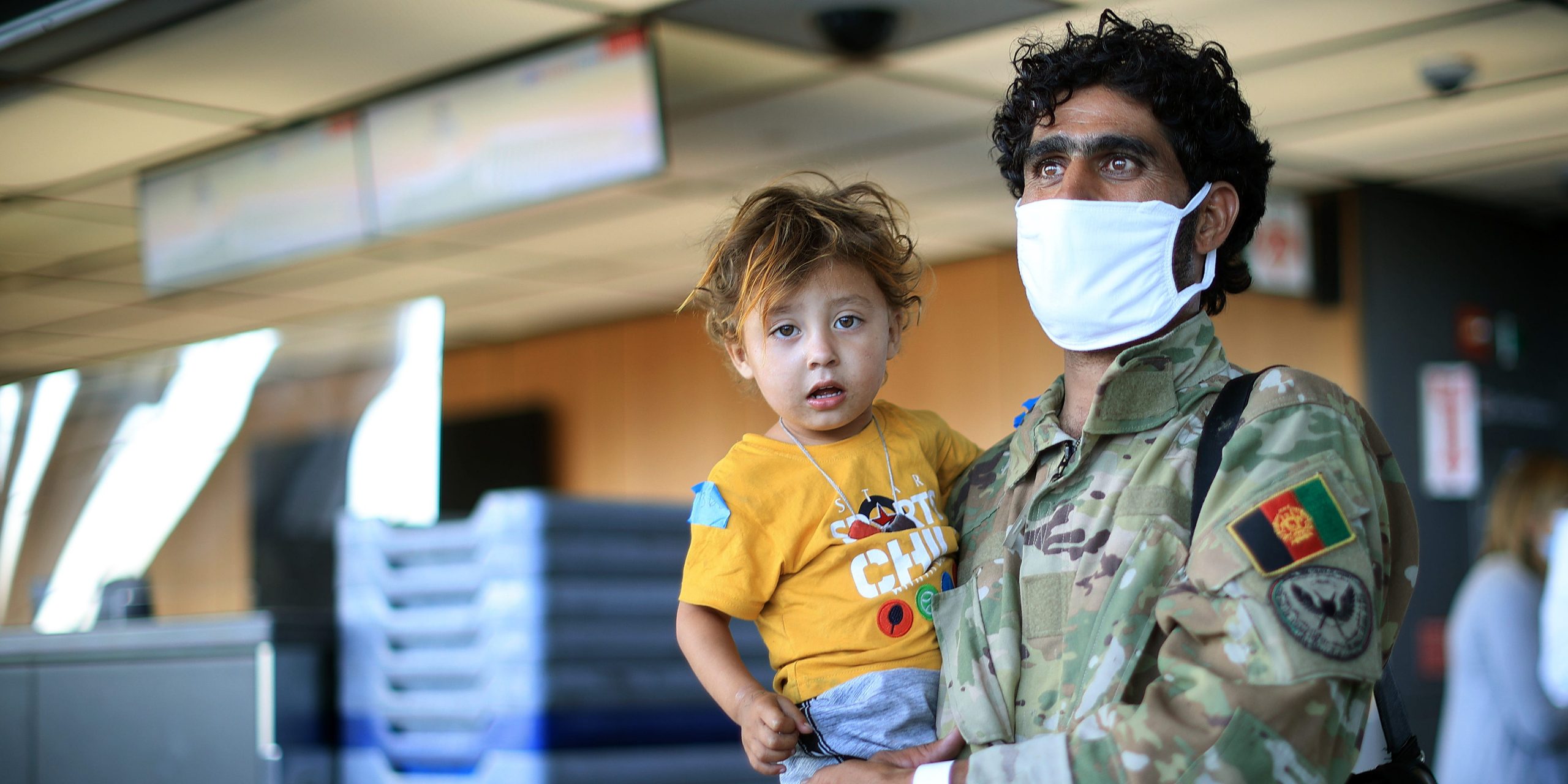 An Afghan refugee holds his child at the airport.
