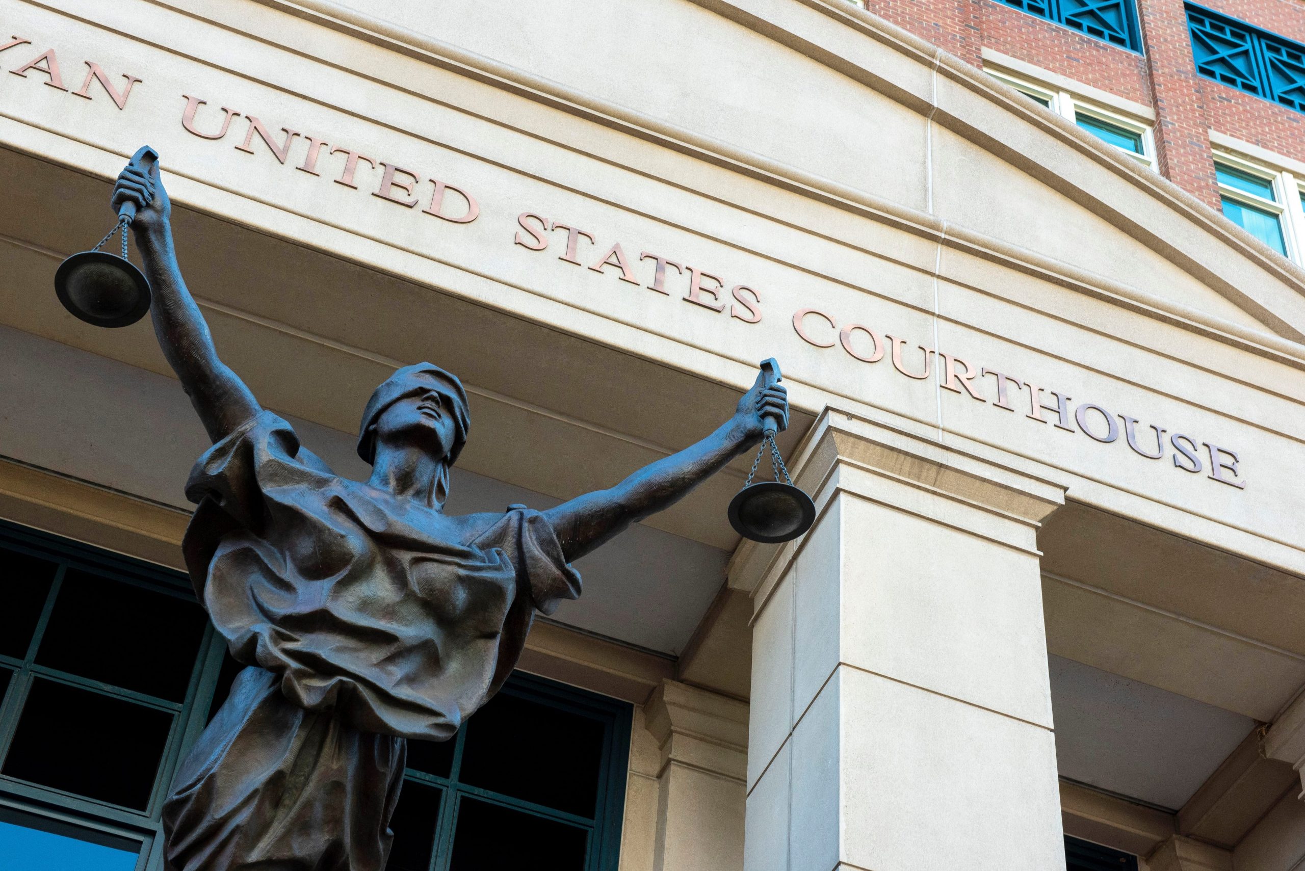 A statue of blind justice in front of a US District Courthouse