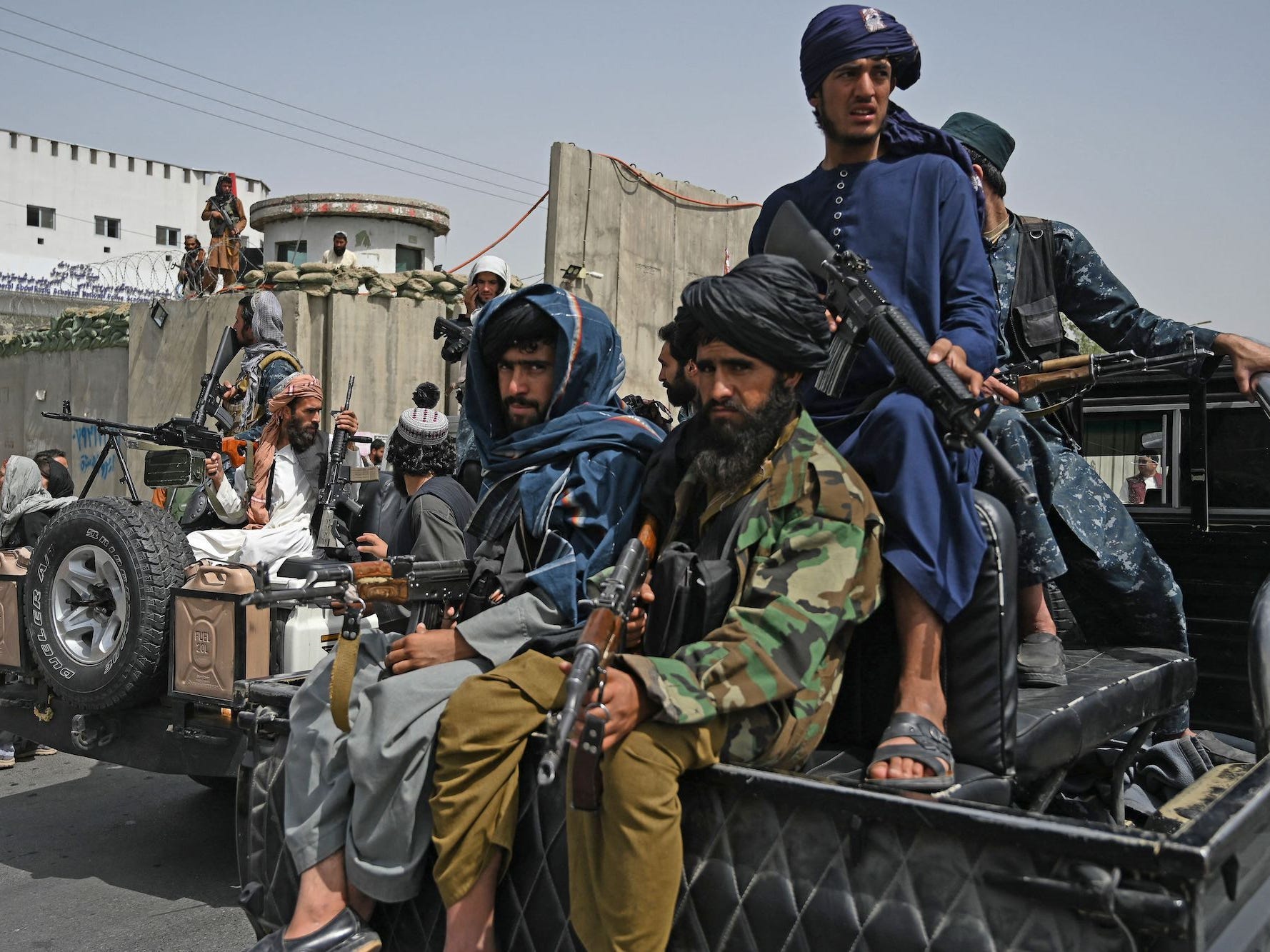 Taliban fighters holding guns on the back of a truck
