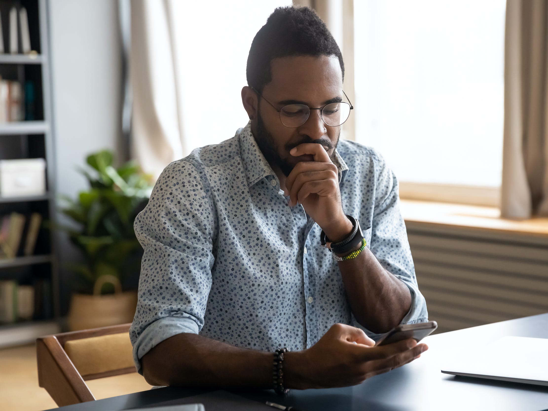 Man looking at phone at desk at home