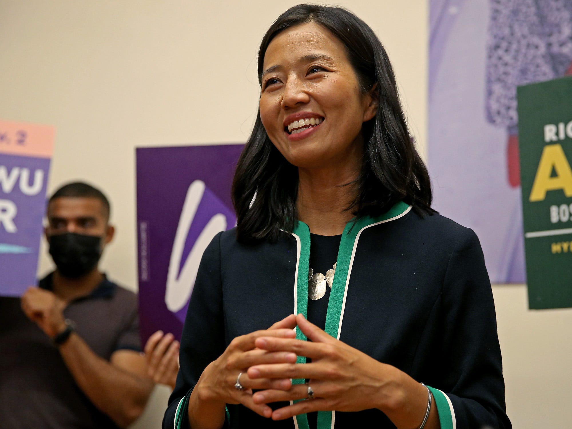 Boston mayoral candidate Michelle Wu wearing a navy blue jacket with teal trim surrounded by supporters