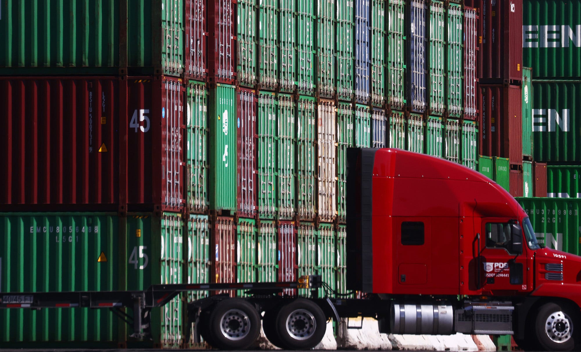 A truck drives past cargo containers stacked at the Port of Los Angeles, the nation’s busiest container port, on October 15, 2021 in San Pedro, California.