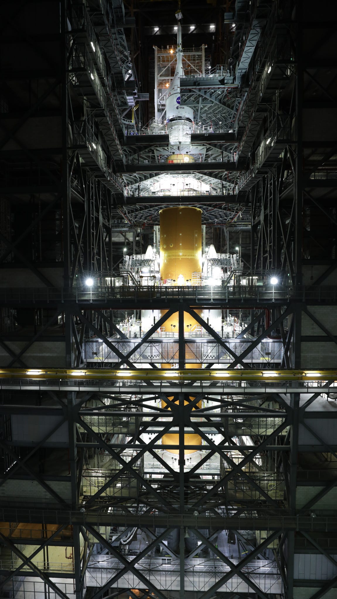 space launch system tall orange rocket standing inside tiered platforms