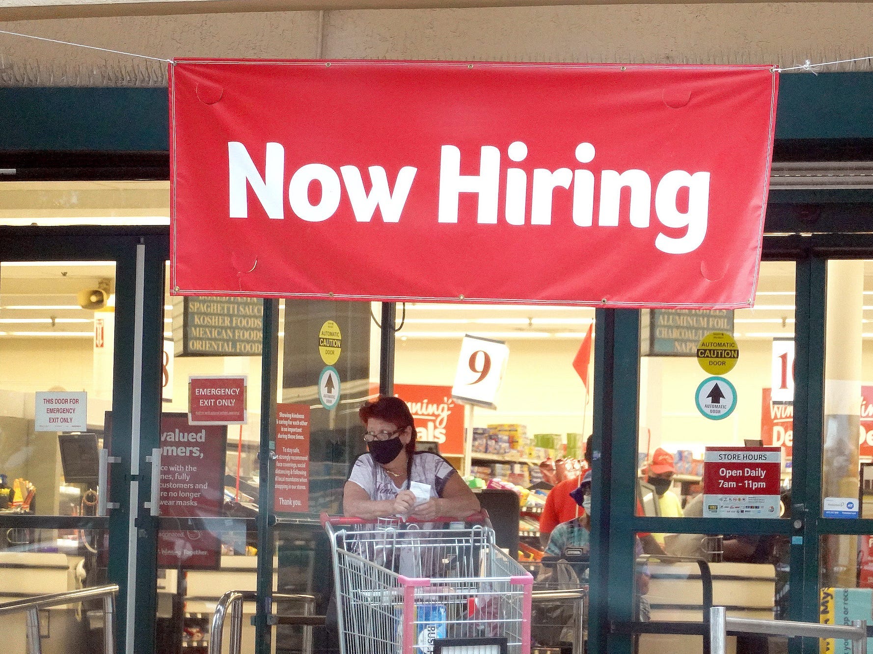 A Now Hiring sign hangs near the entrance to a Winn-Dixie Supermarket