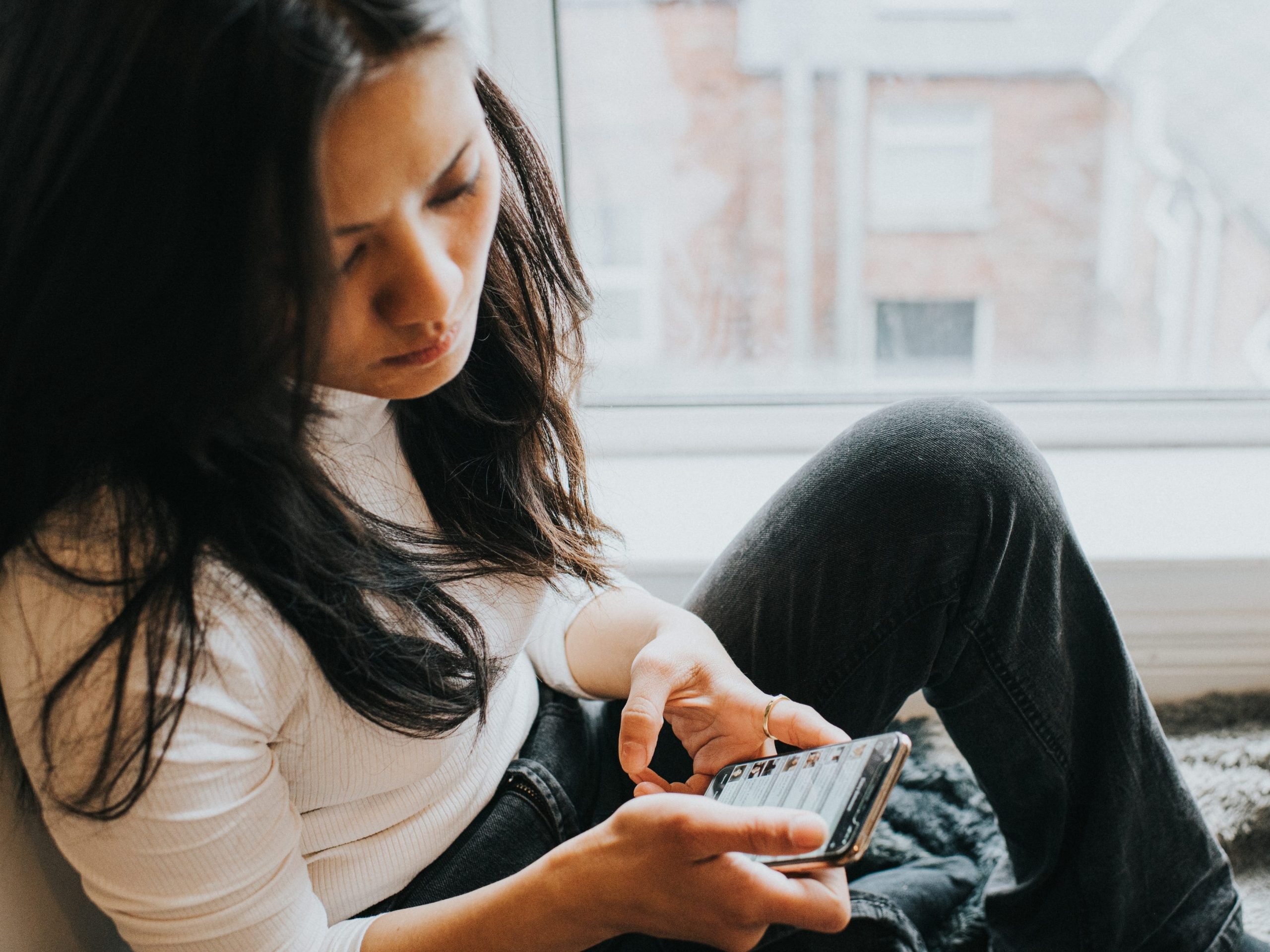 A perplexed woman checks her smart phone