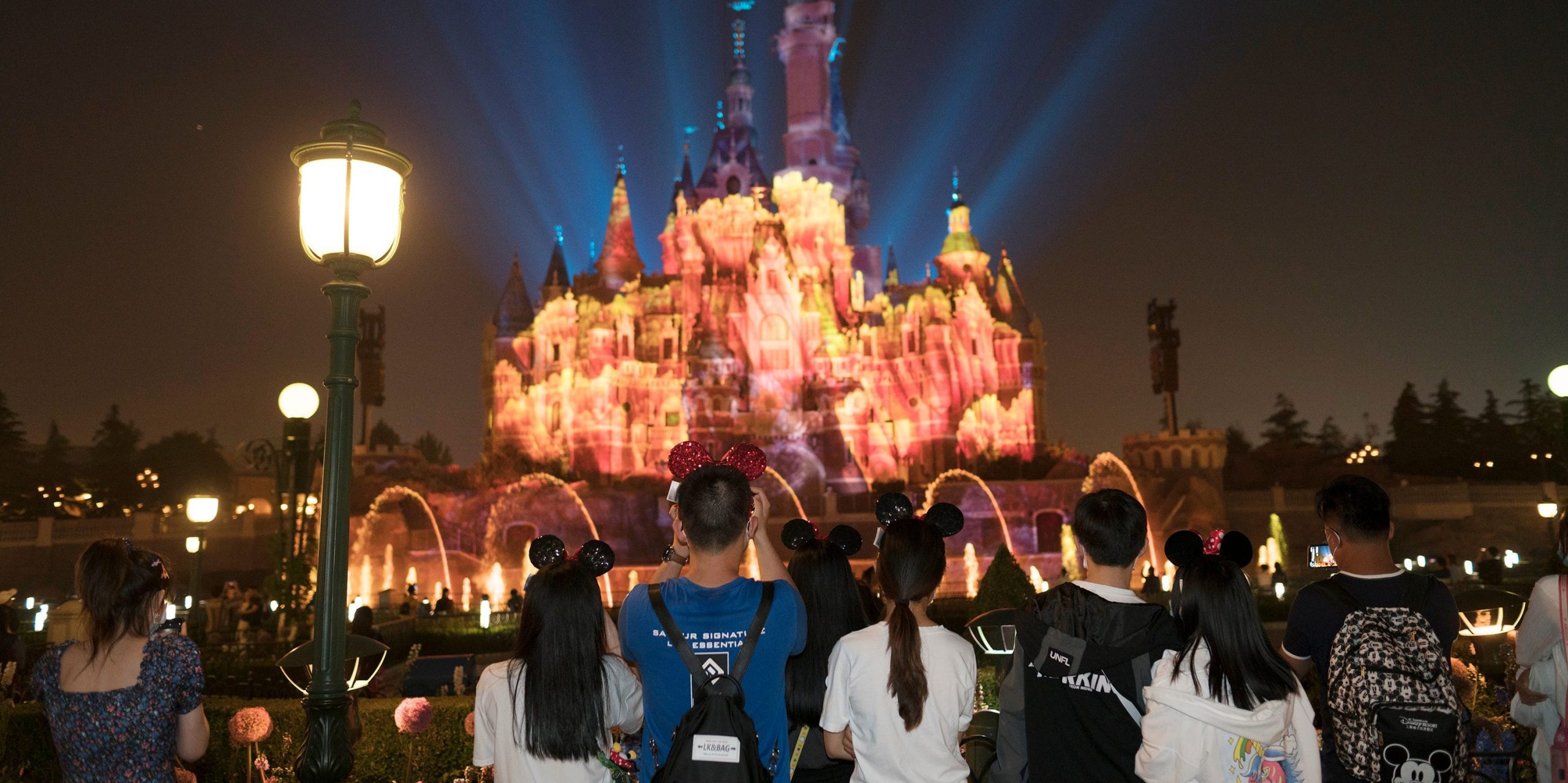 This image shows Disneyland and night while people look at lights behind the castle.