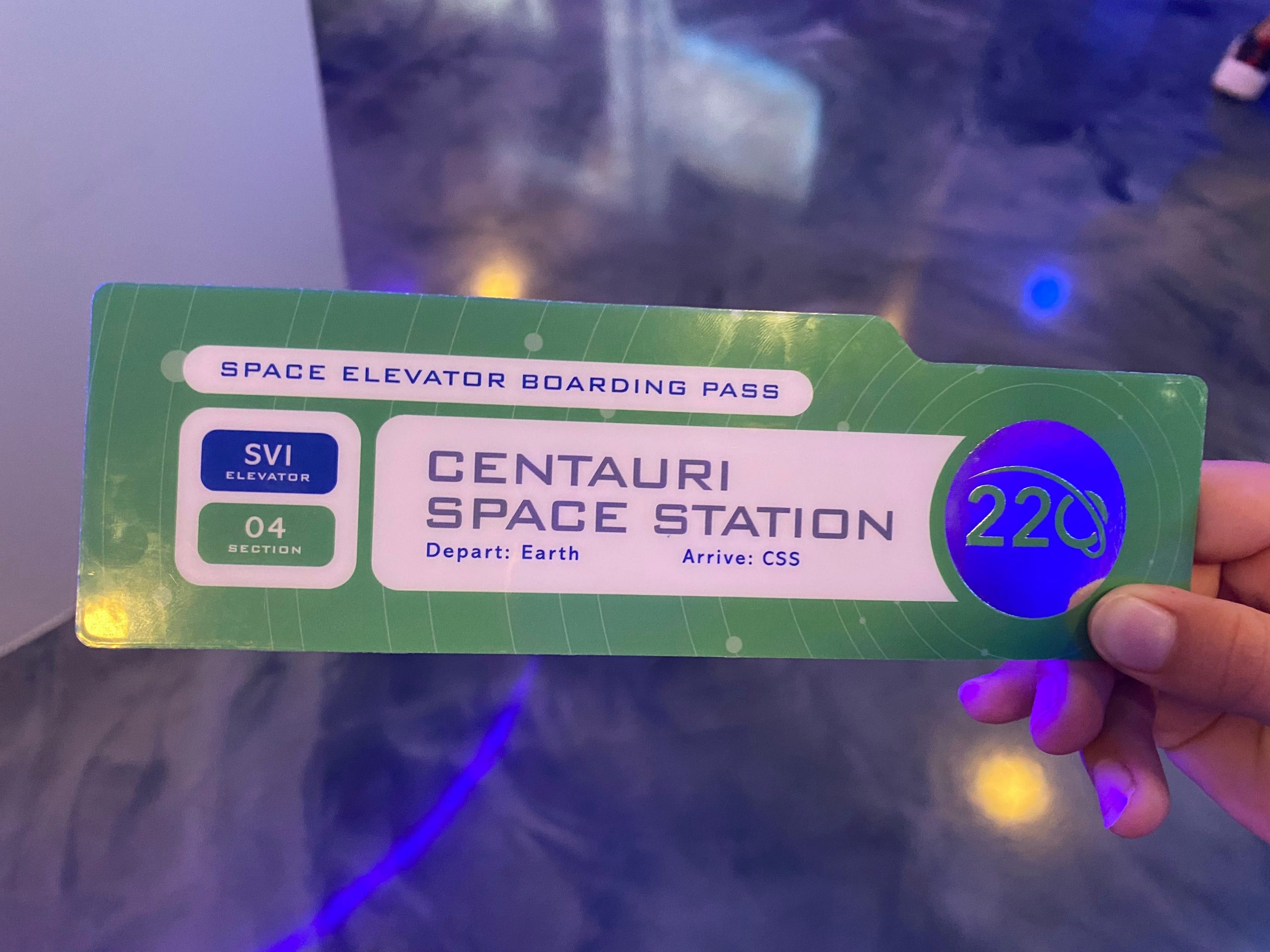 hand holding boarding pass for space 220 elevator epcot disney world