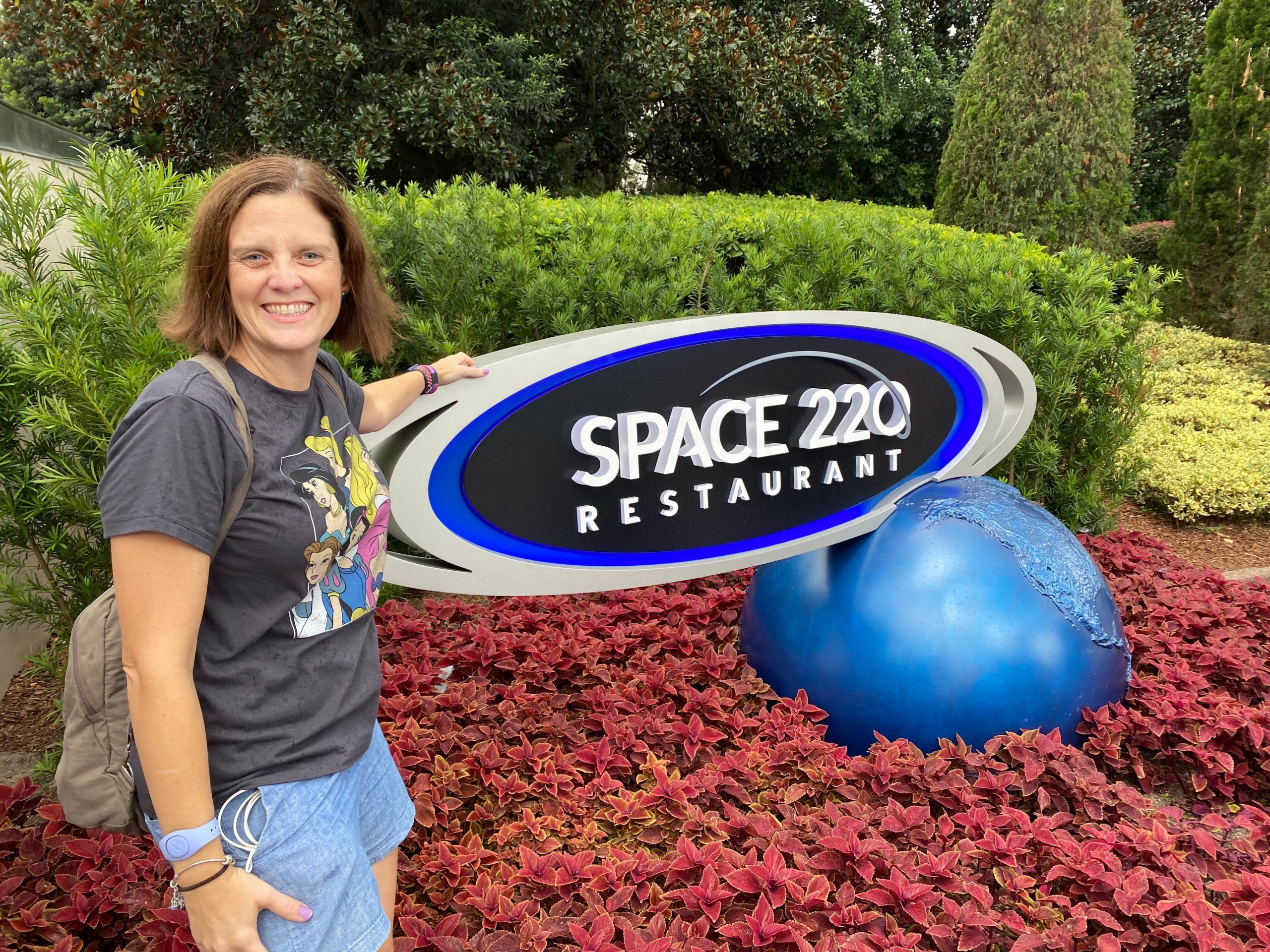 kari standing next to the space 220 restaurant sign at epcot disney world