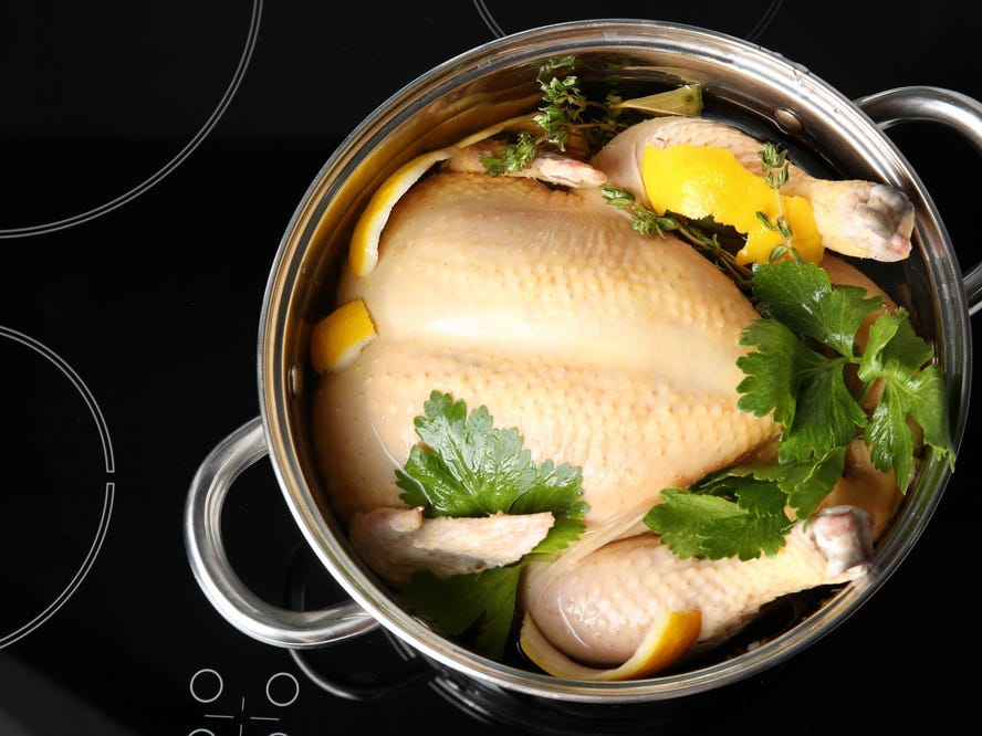 Cooking pot with turkey soaked in flavored brine on electric stove.