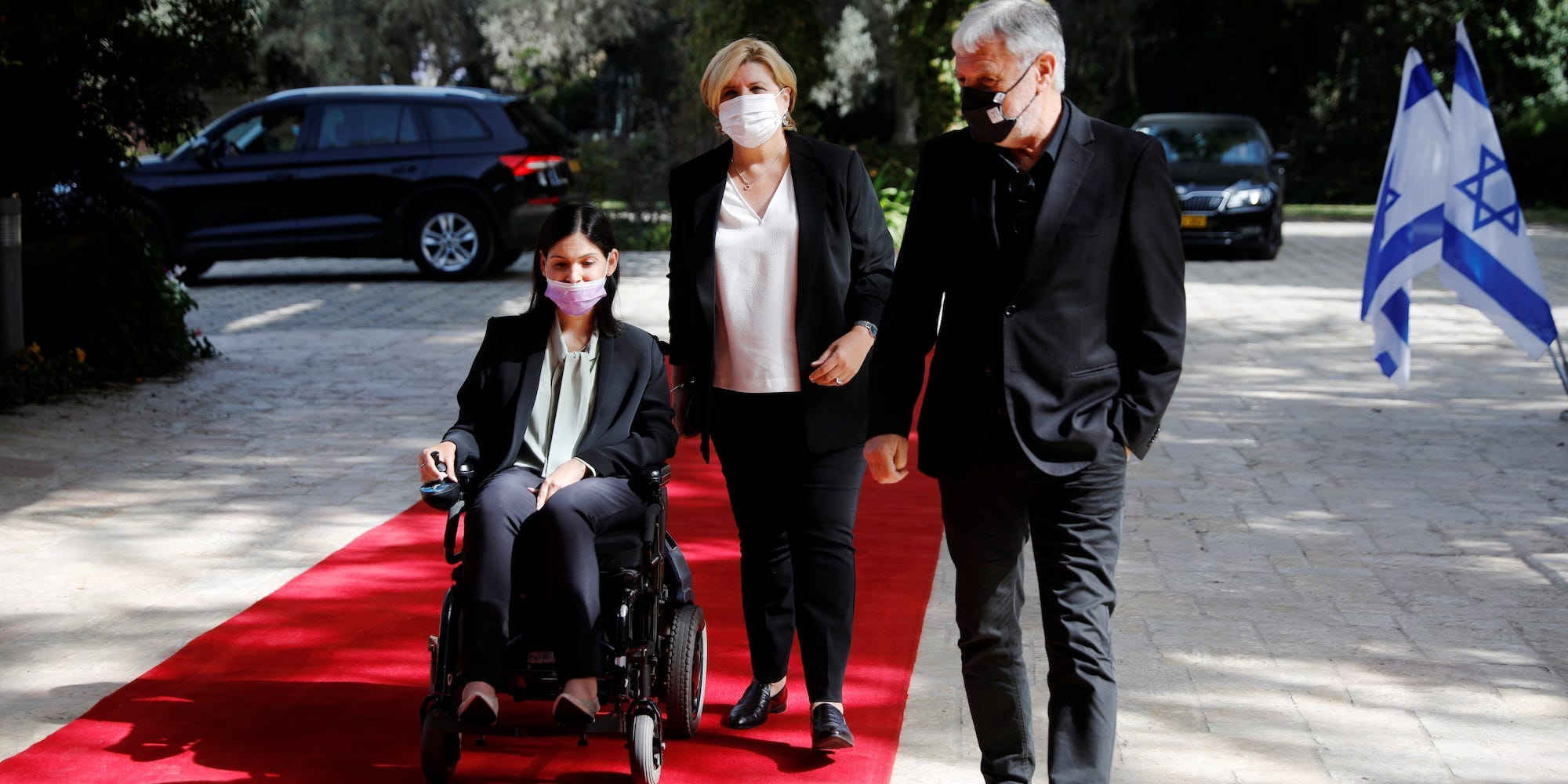 Karine Elharrar in a wheelchair on a red carpet outside