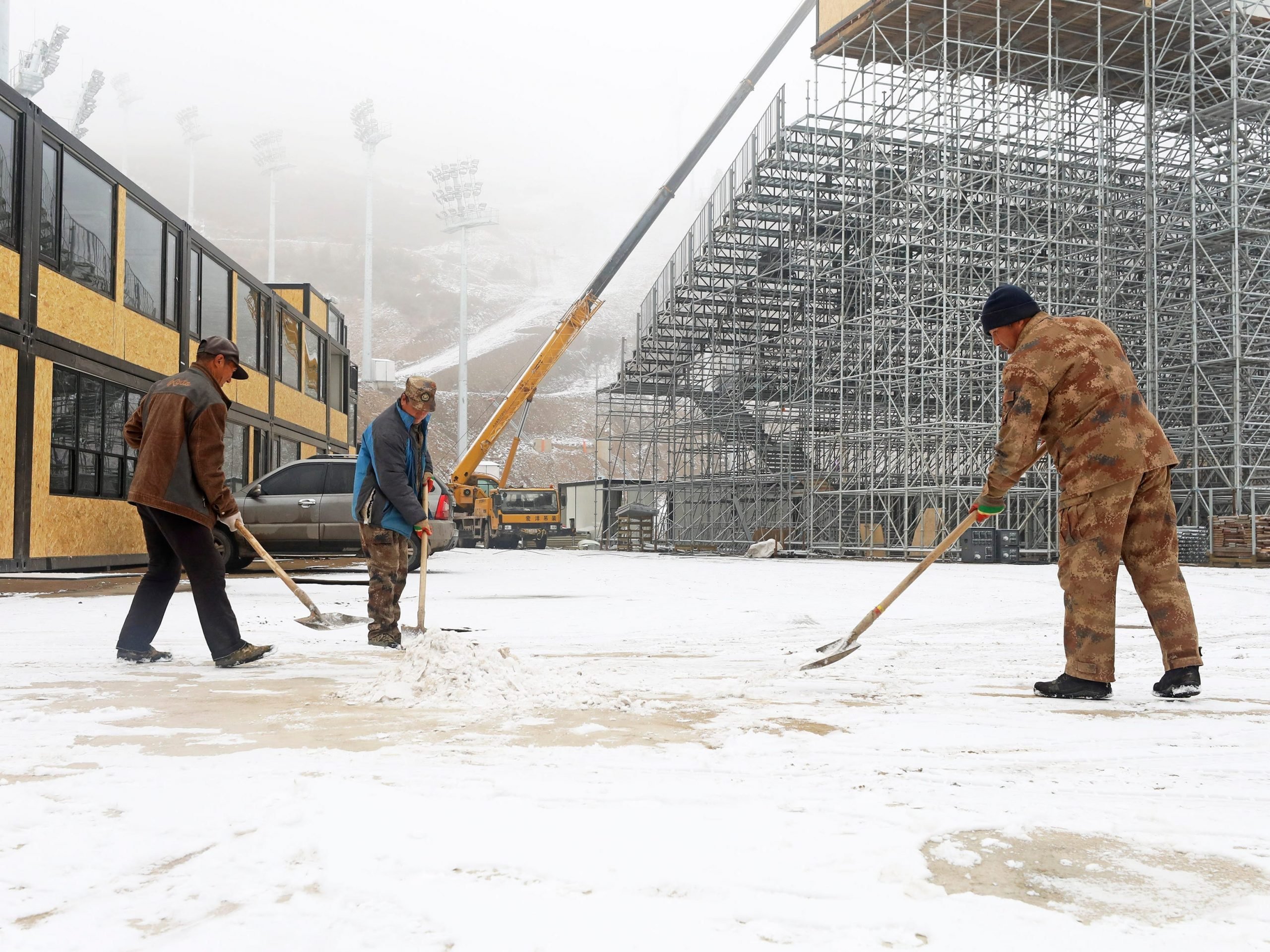 Workers clean snow at the Genting Snow Park, venue for freestyle skiing and snowboarding matches of Beijing 2022 Winter Olympics.