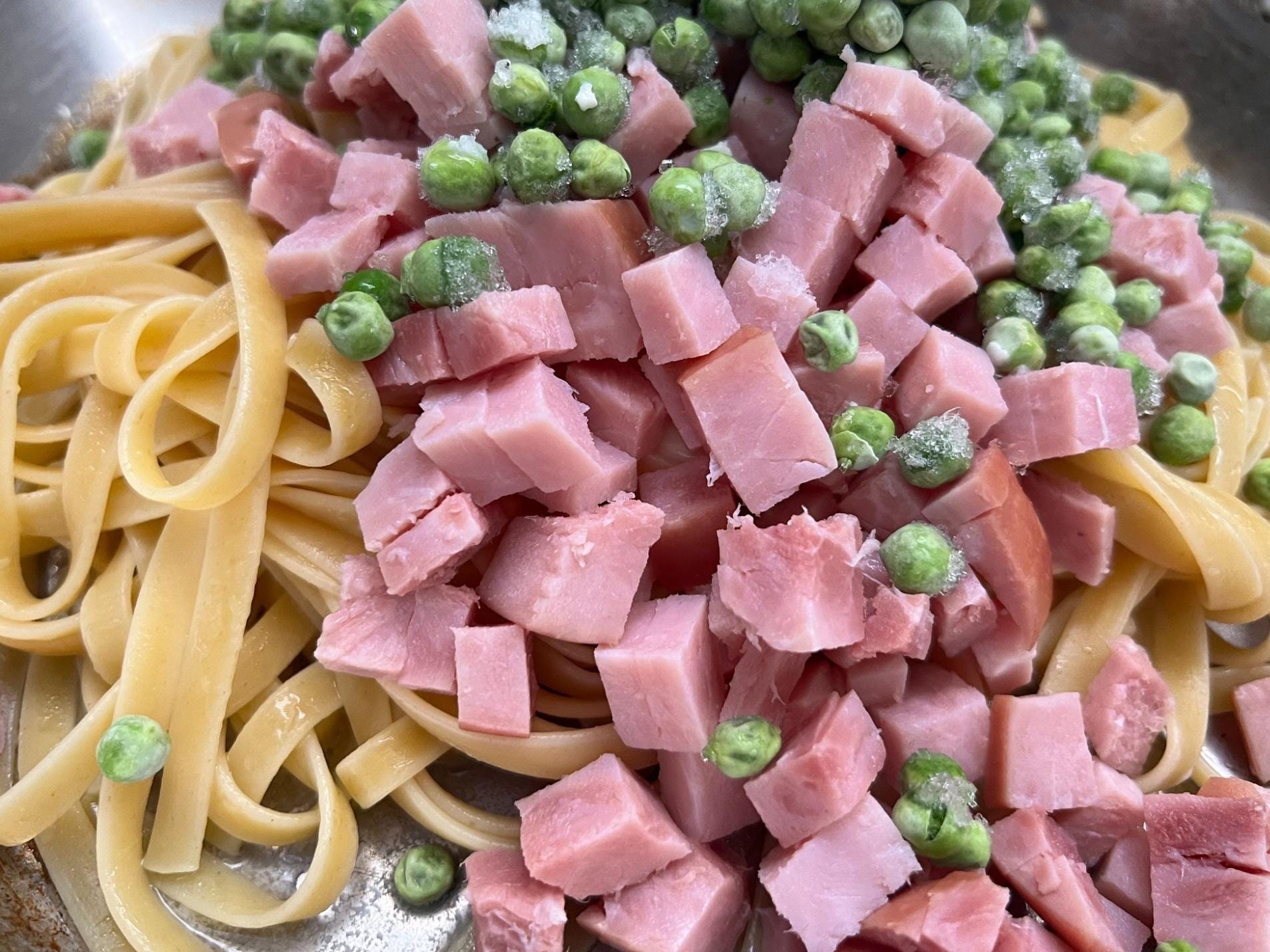 Ham, peas, and noodles in a pan.