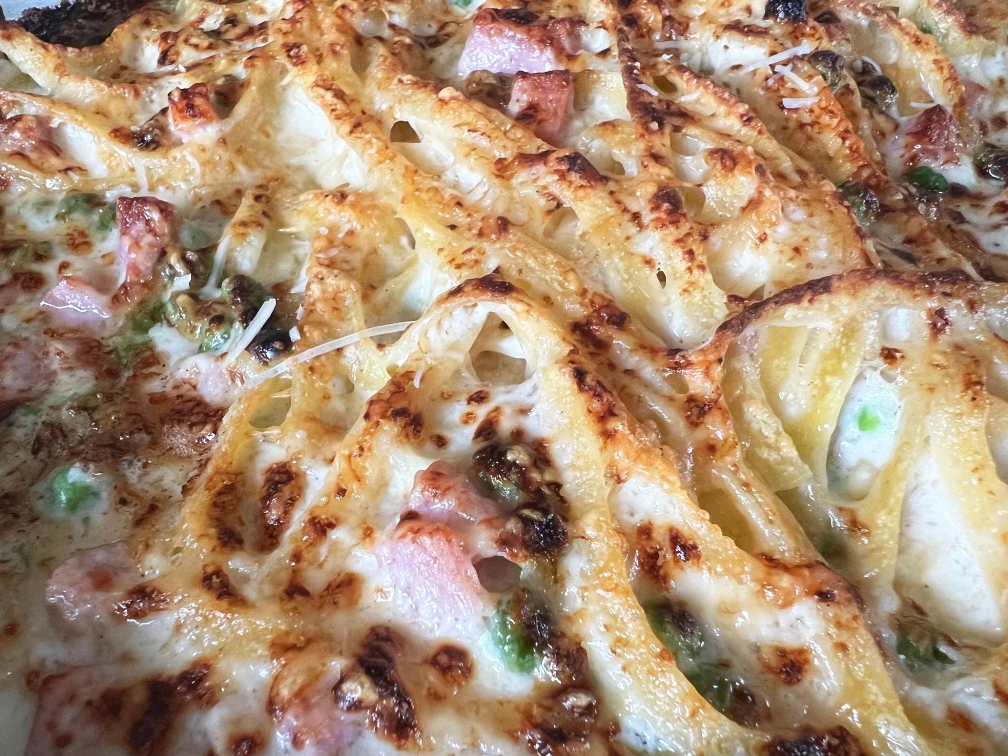 Baked pasta with ham and cheese and peas.