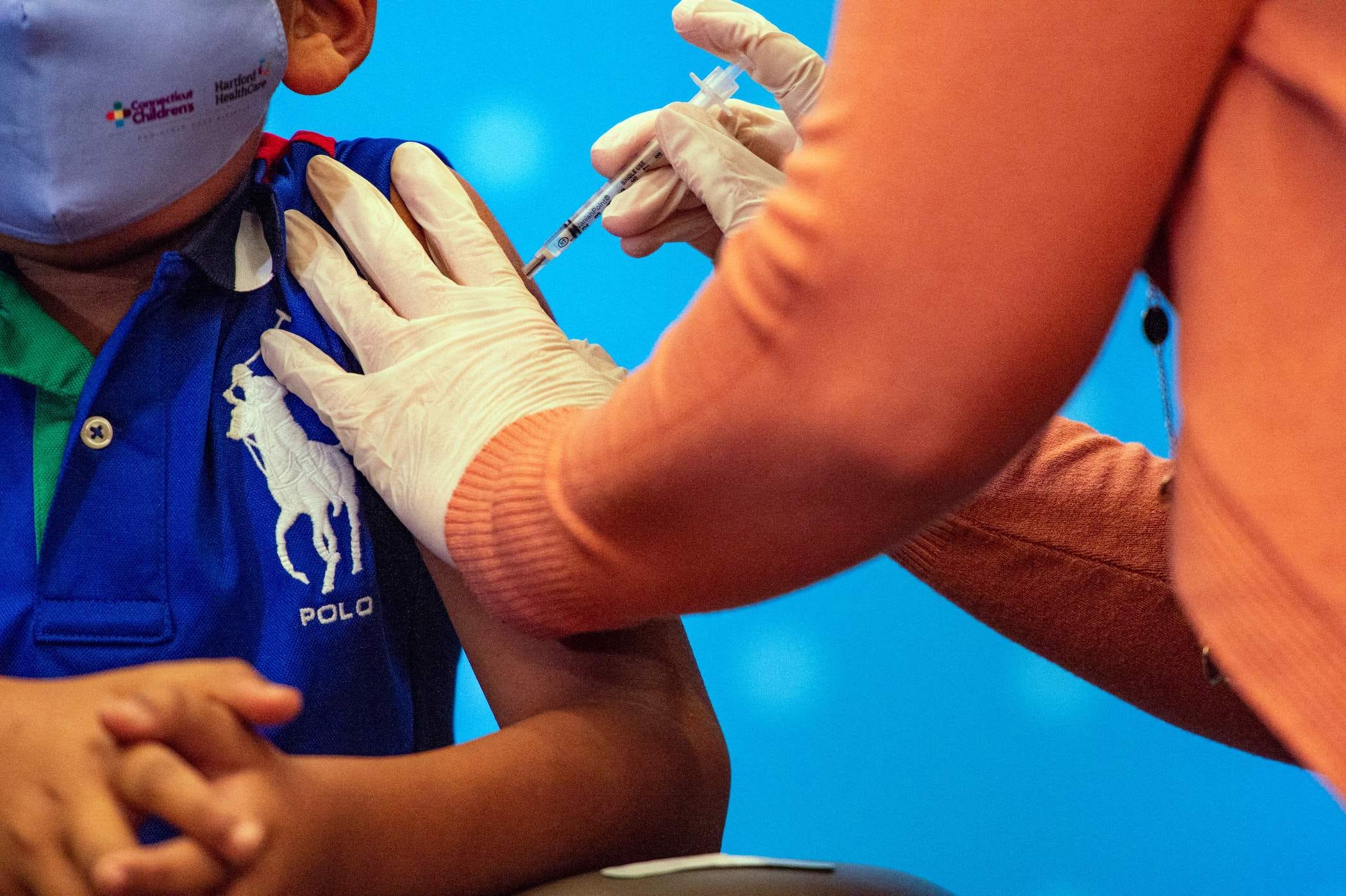 a chlid's arm getting injected with pfizer's covid-19 vaccine