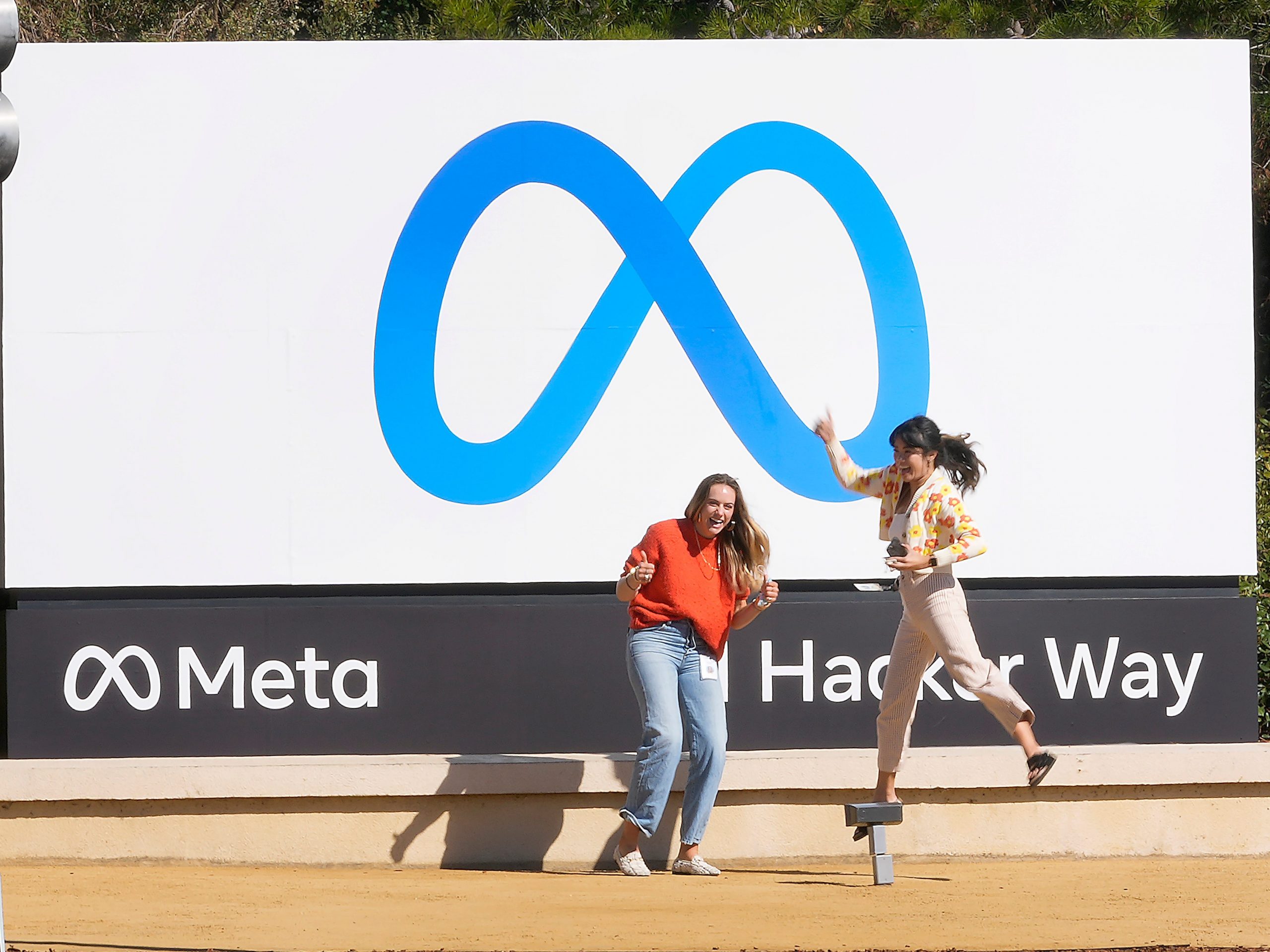 Facebook employees in front of the company's new Meta sign at 1 Hacker Way