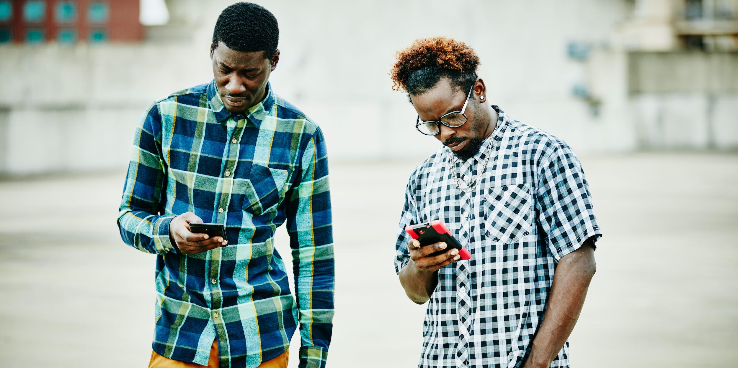 friends looking at phones standing outside in city