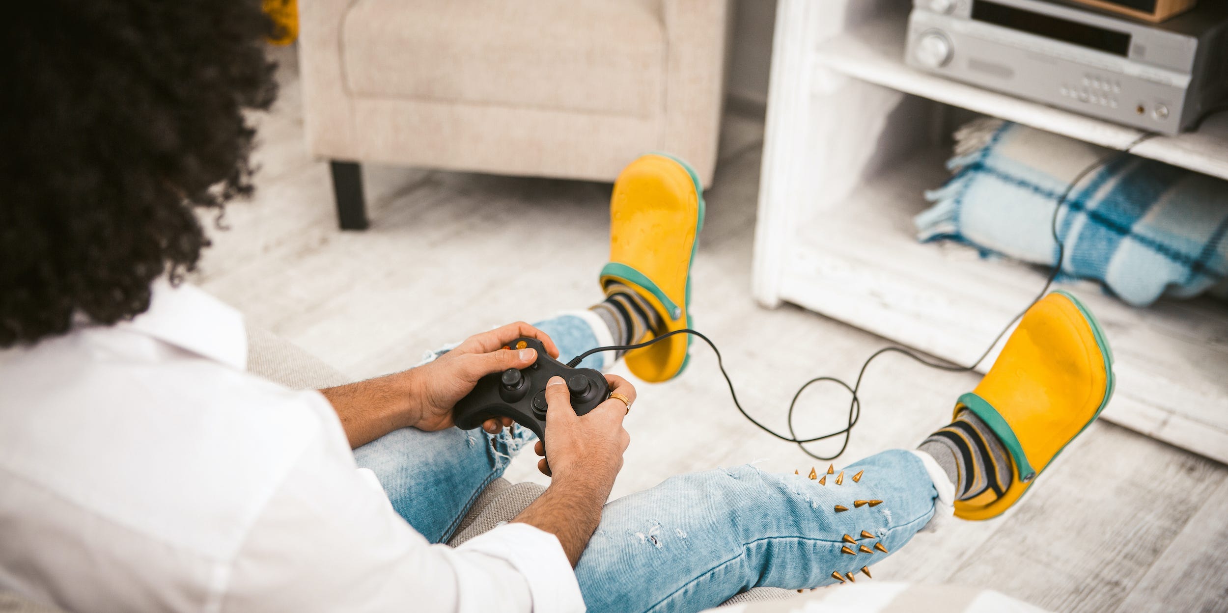 man gaming with controller in hand at home in front of tv