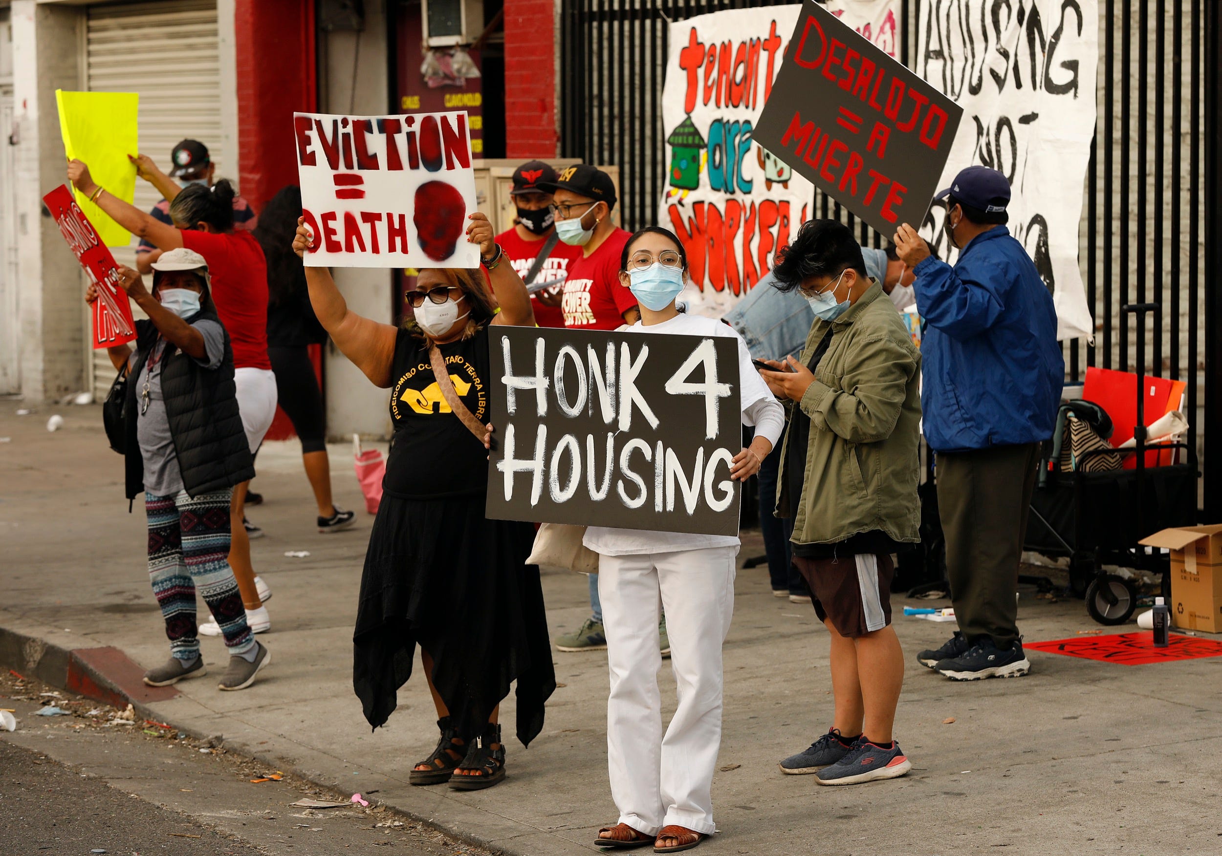 A group of housing advocates and tenants with signs stand in front of an apartment building in Los Angeles, California, to protest evictions.
