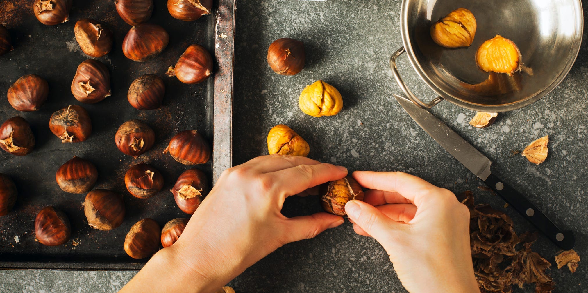 A persons hands peeling chestnuts