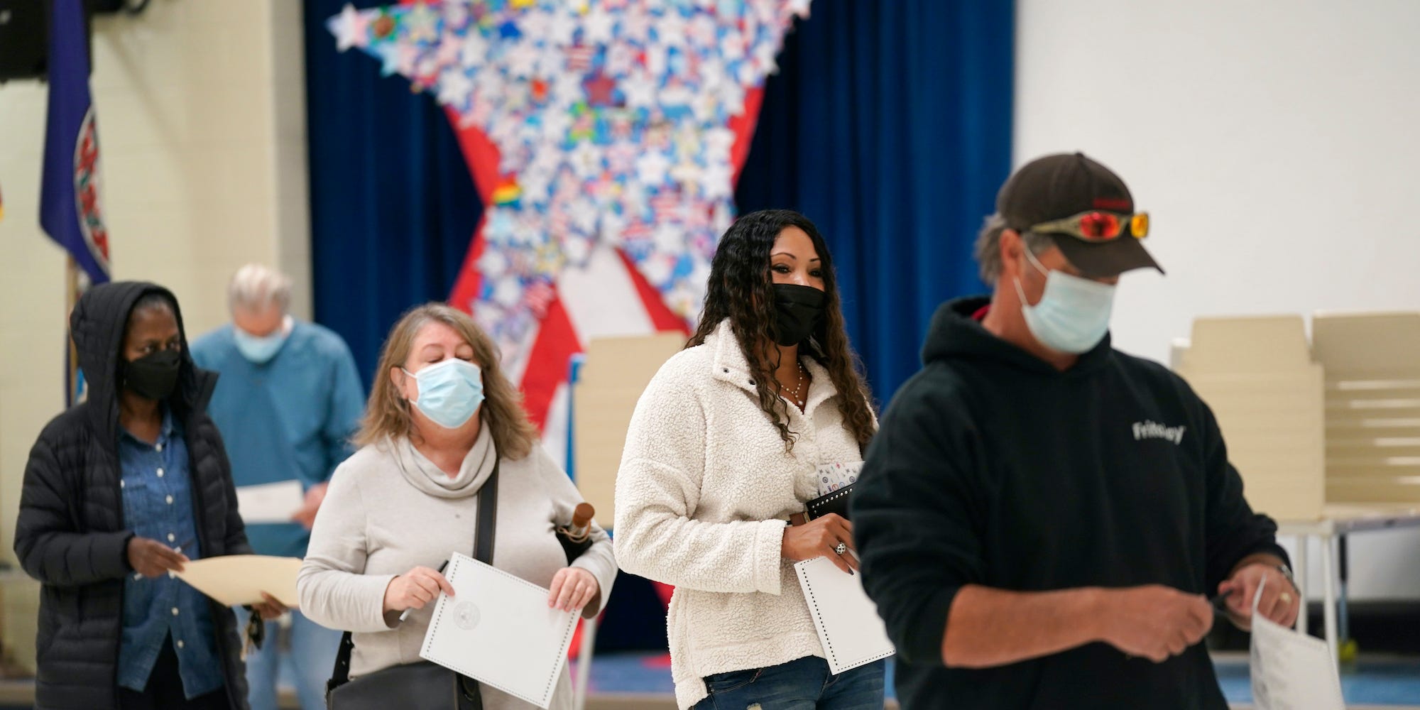 Voters hold their ballots as they wait in line to register their votes at a school in Midlothian, Va., Tuesday, Nov. 2, 2021.