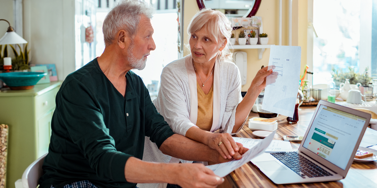 Senior couple sitting in front of a laptop at home doing their finances together.