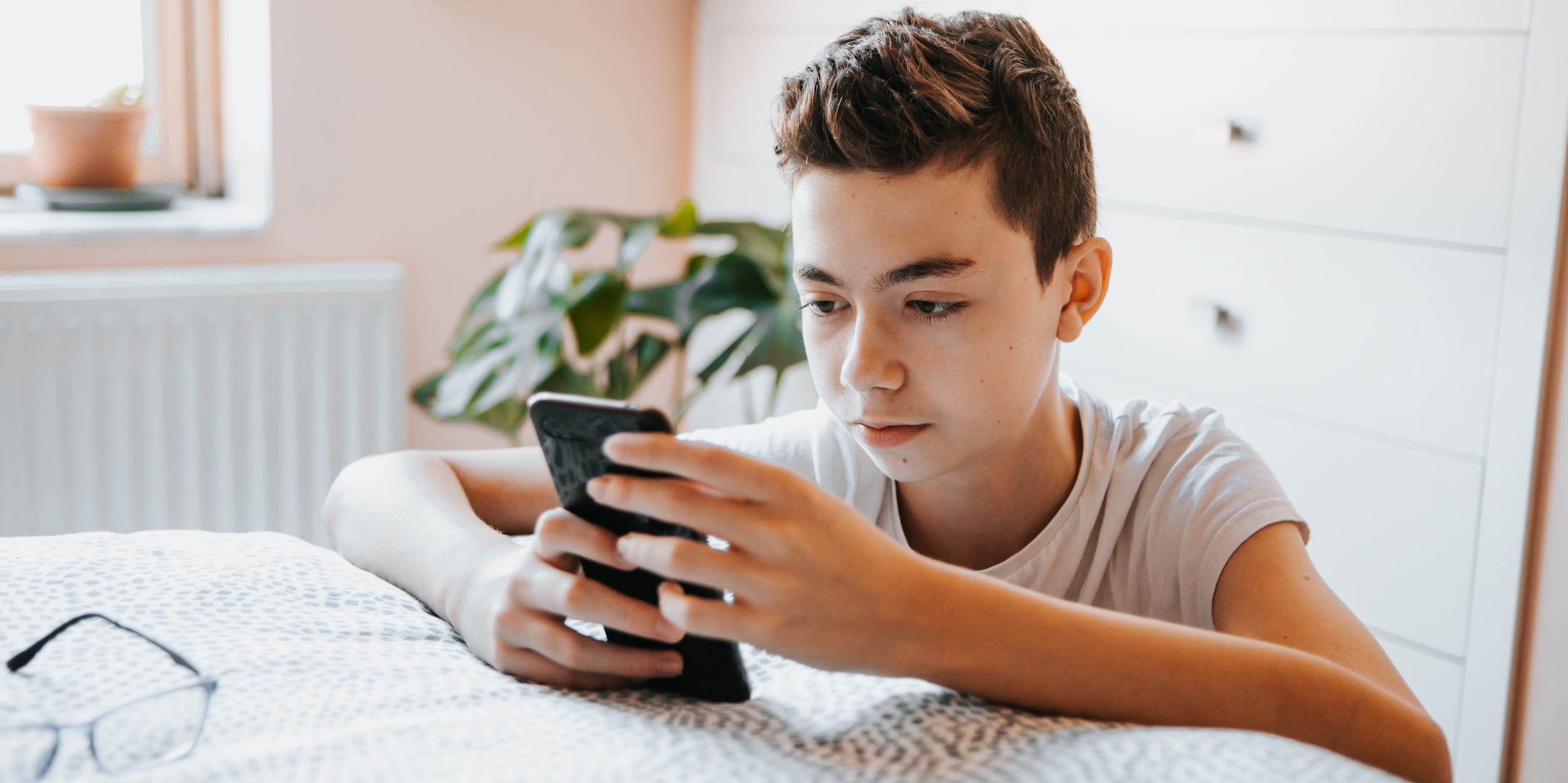 teenager texting on phone at home in bedroom