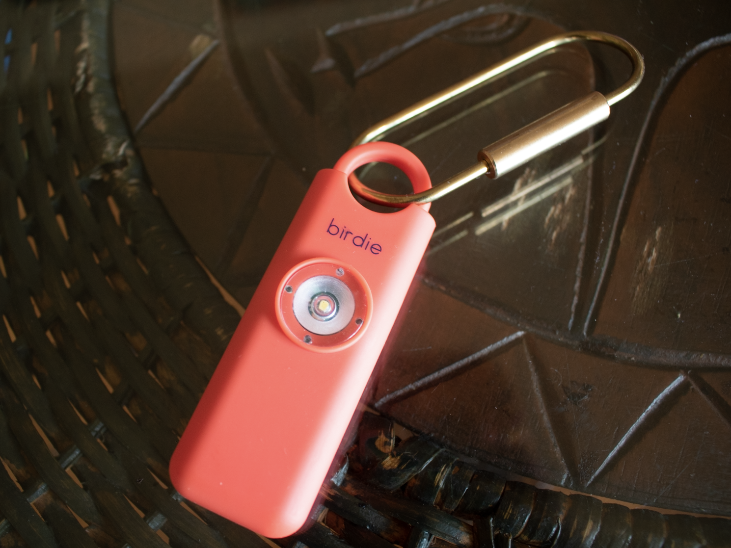 Pink personal safety alarm on a key ring on a brown table