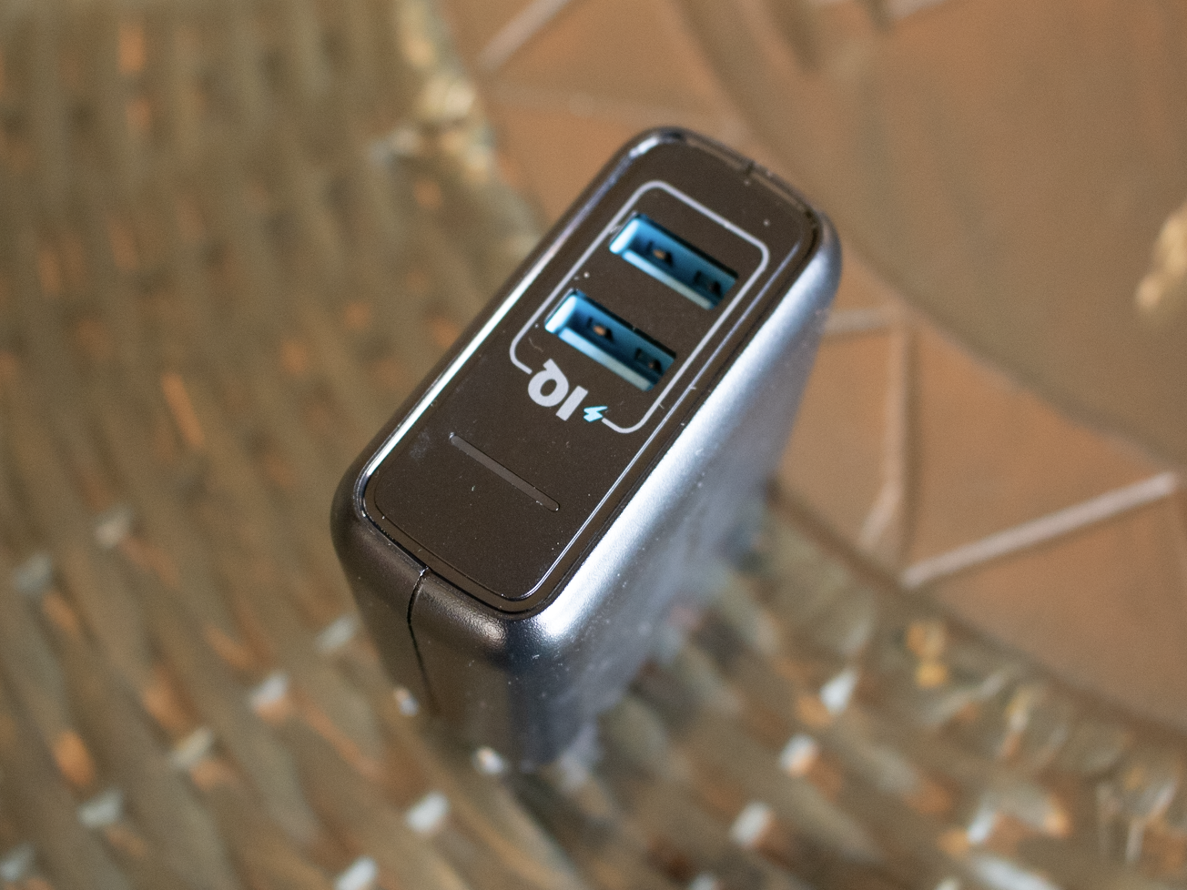 Black portable plug-in USB charger on a brown table