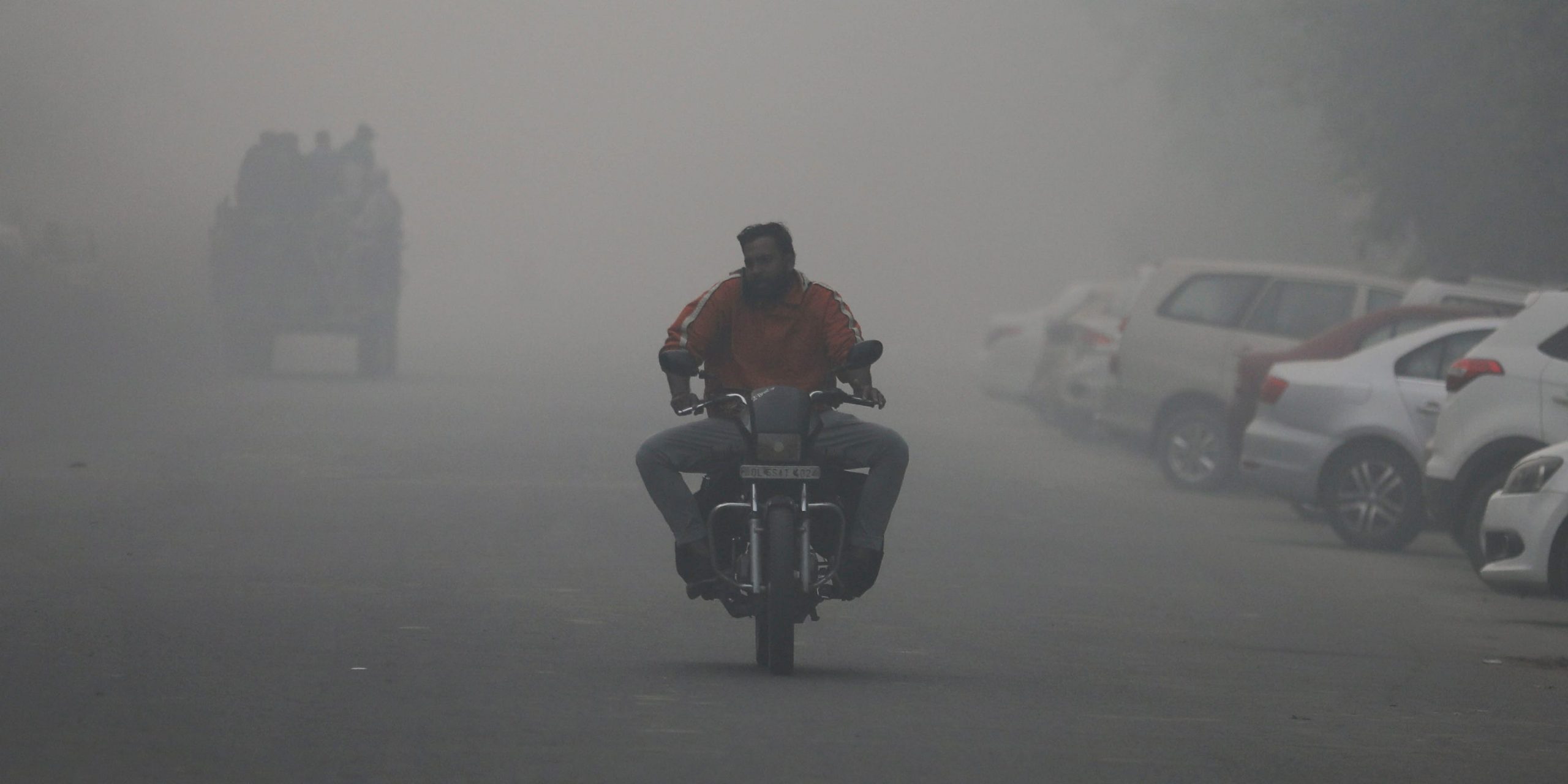 A man rides a motorbike, surrounded by smog