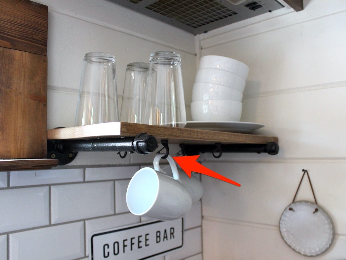 An arrow points to hooks where coffee mugs were stored in the tiny house.
