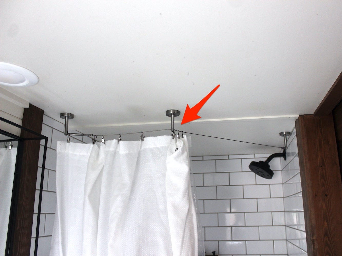 An arrow points to a wire that served as the tiny house's shower rod.