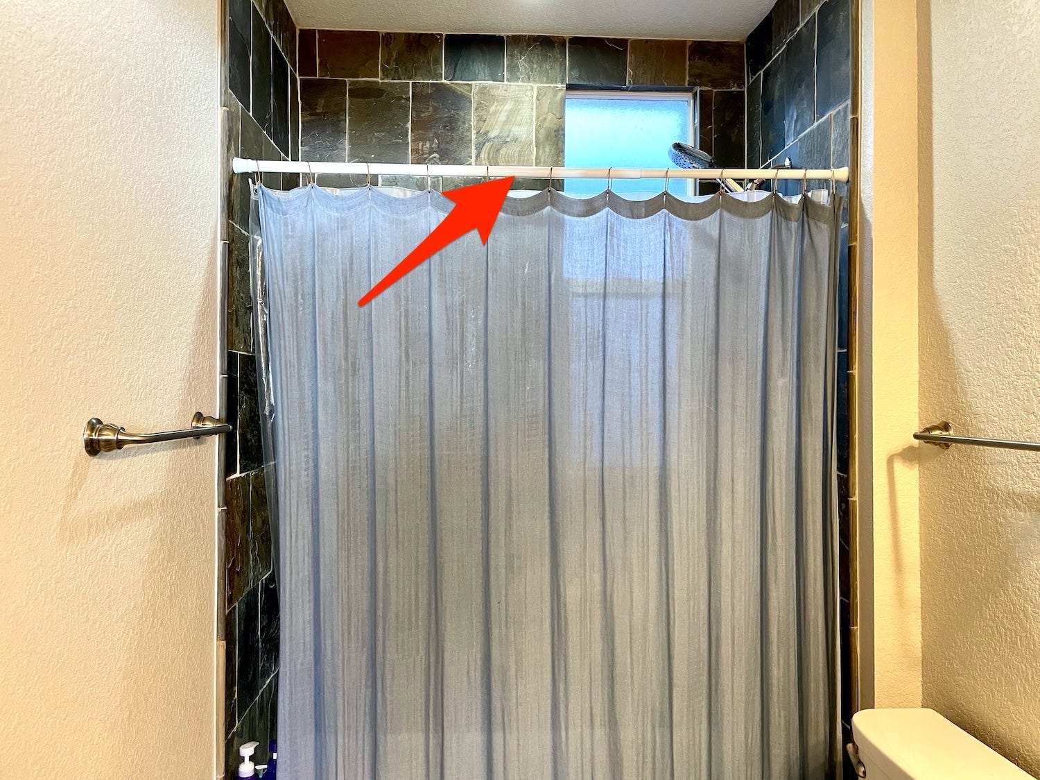 An arrow points to our current shower rod.