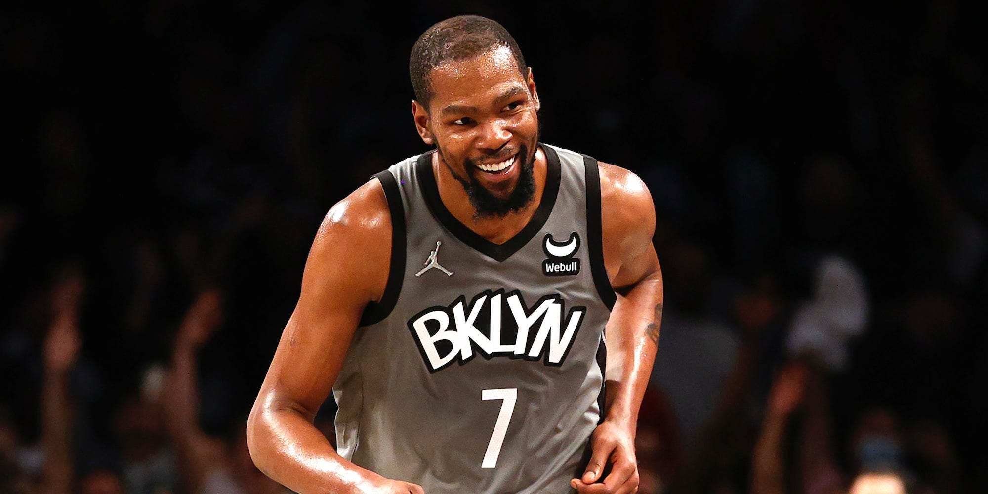 Kevin Durant smiles while running up the court.