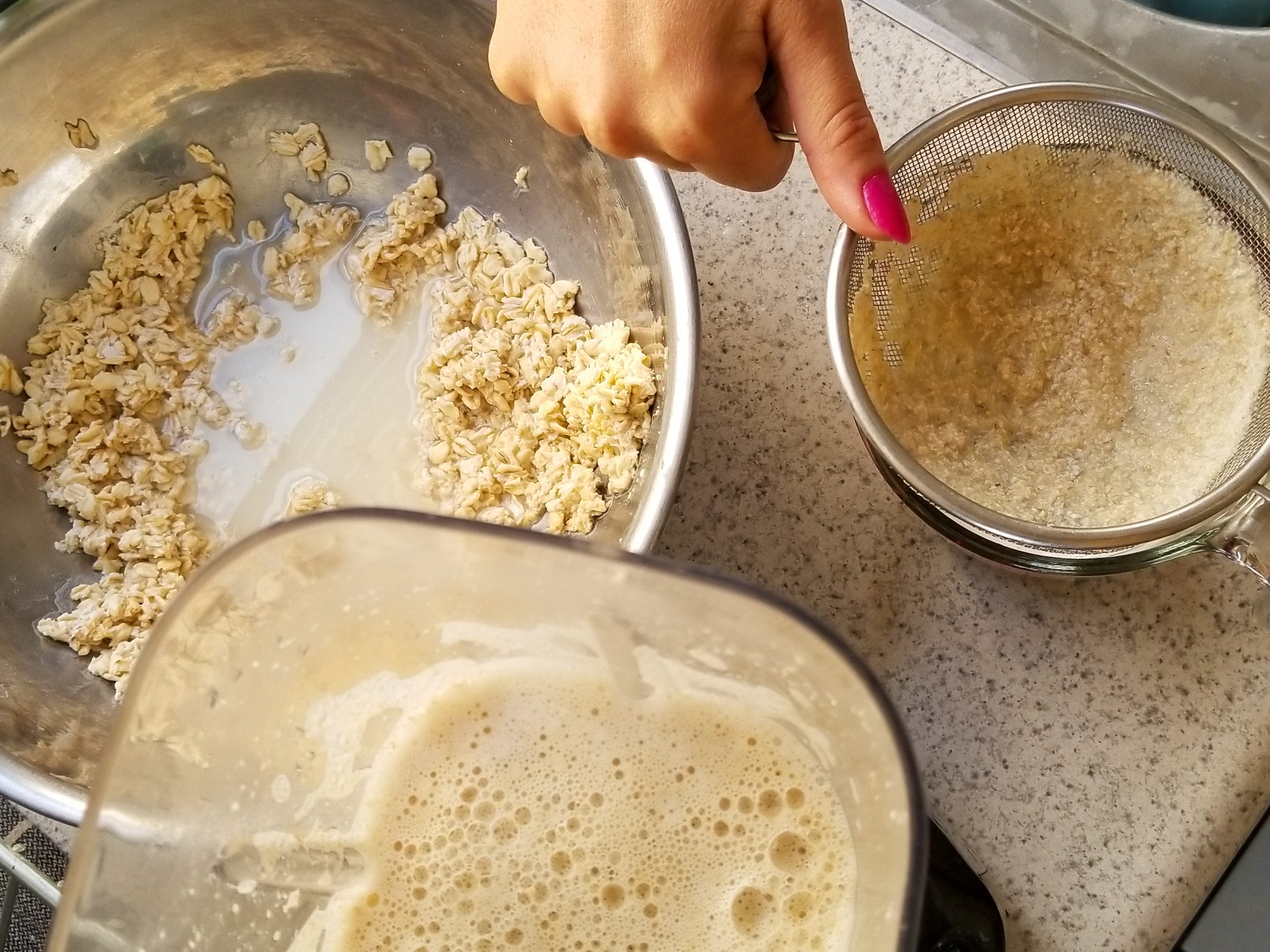 Oat milk getting prepared using a blender and strainer.